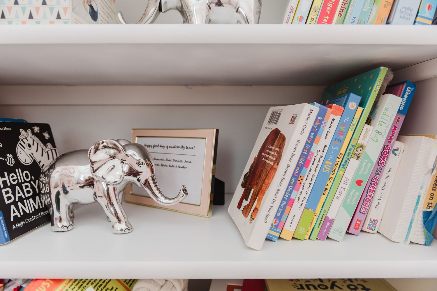 Colorful children's books and decorative elements displayed on white shelving.