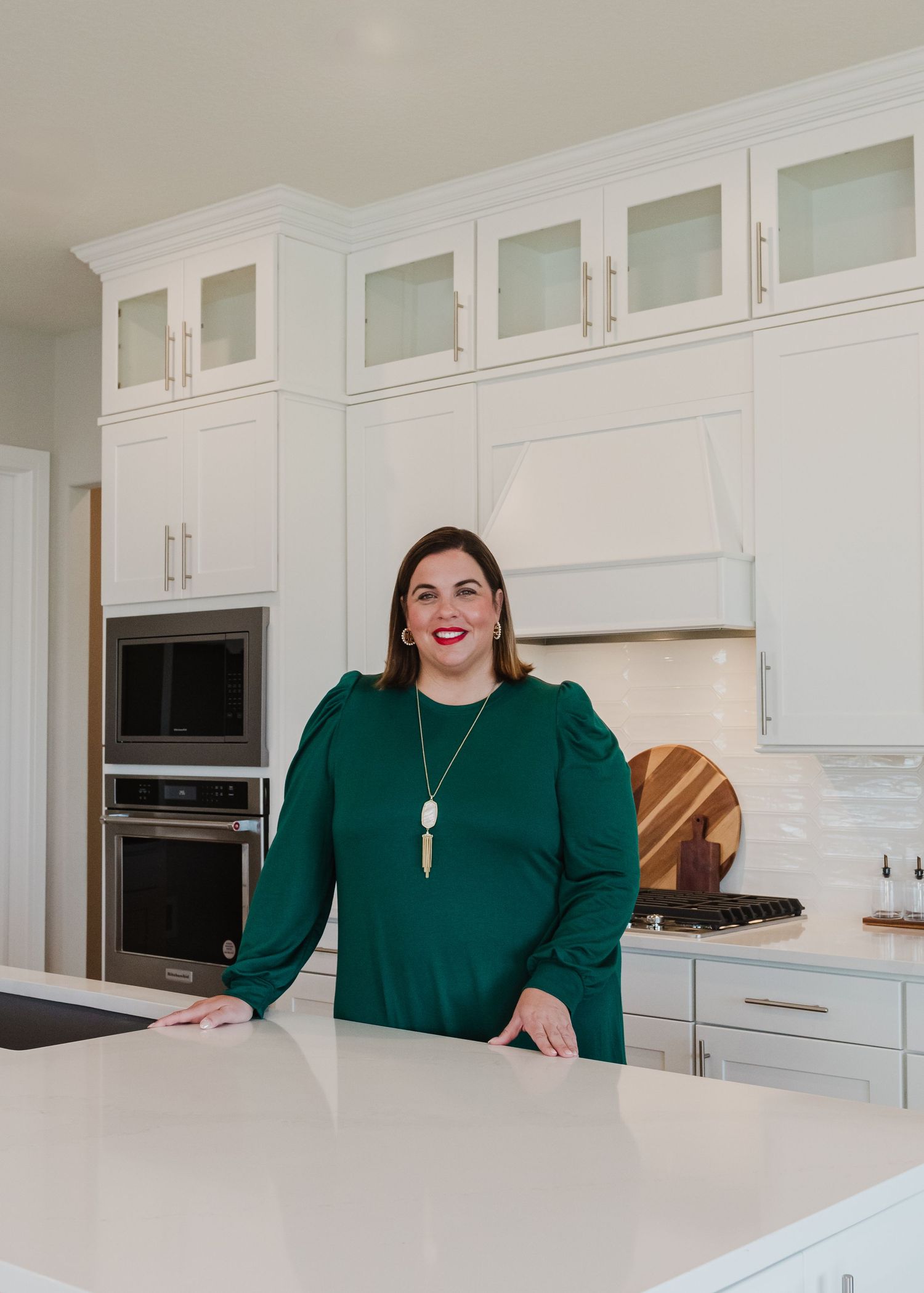 Two colleagues in business attire posing in bright contemporary kitchen setting.