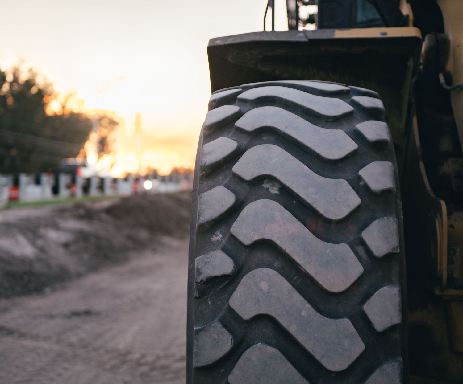 Close-up view of a large construction tire tread pattern at sunset.