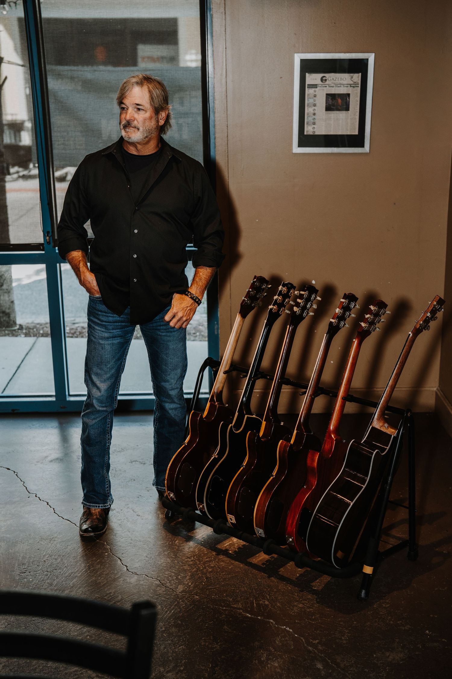 Collection of acoustic guitars displayed on dark floor in music venue.