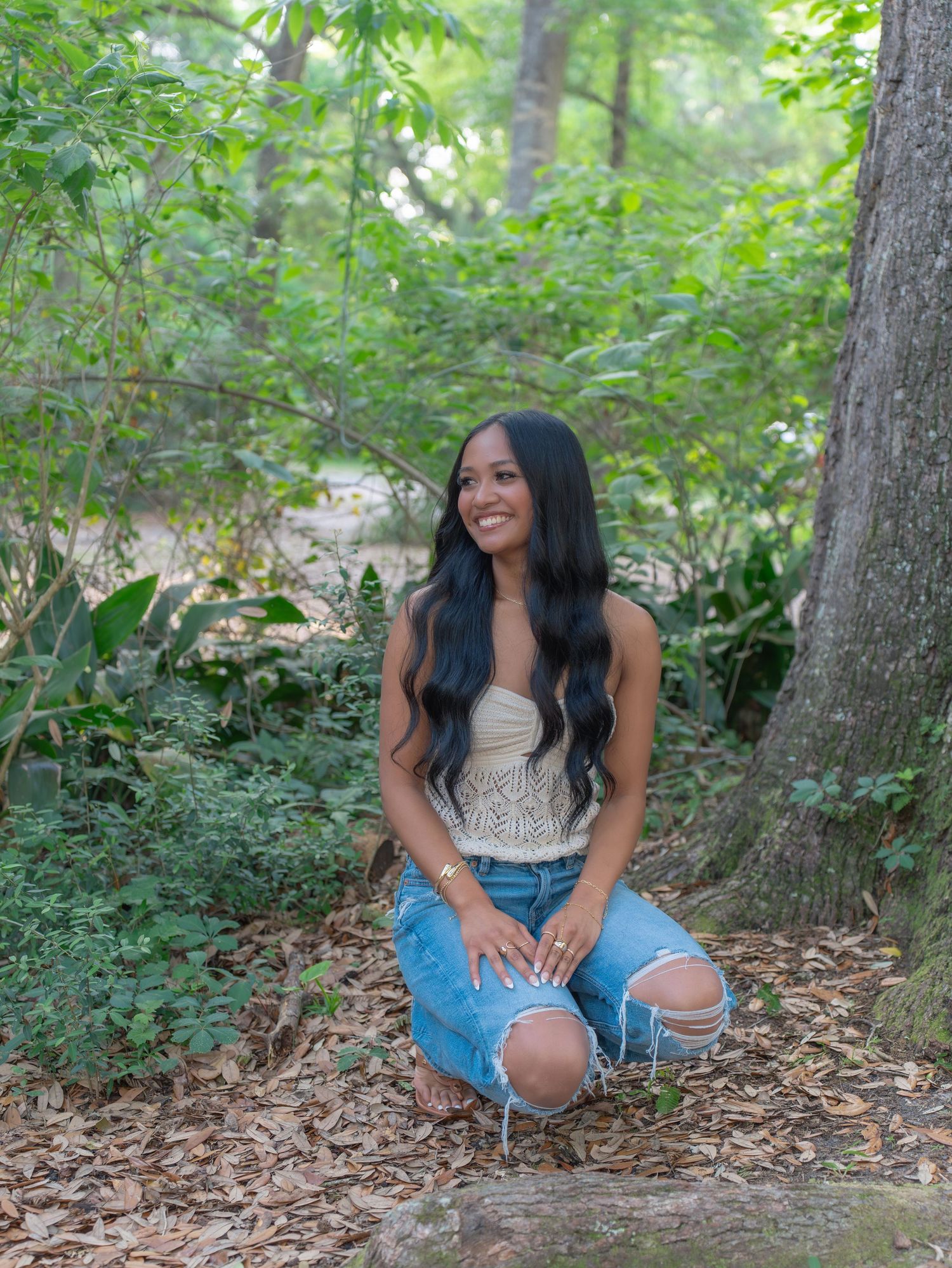 Outdoor portraits in ripped jeans and white top on forest floor.