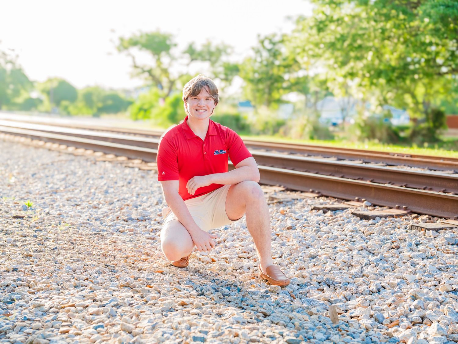 Senior photo session on railroad tracks with red polo shirt.