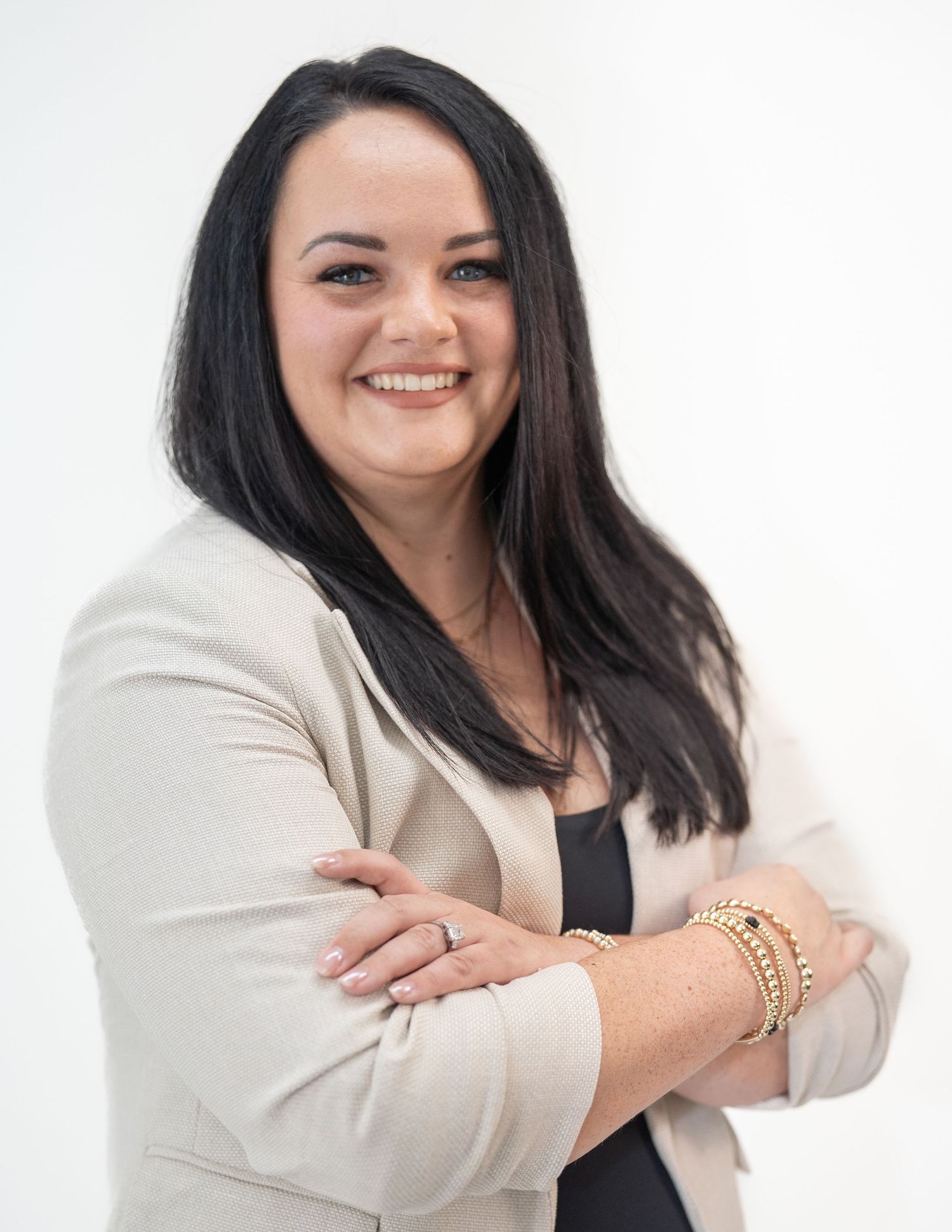 Business portraits in cream blazer and black top against white background.