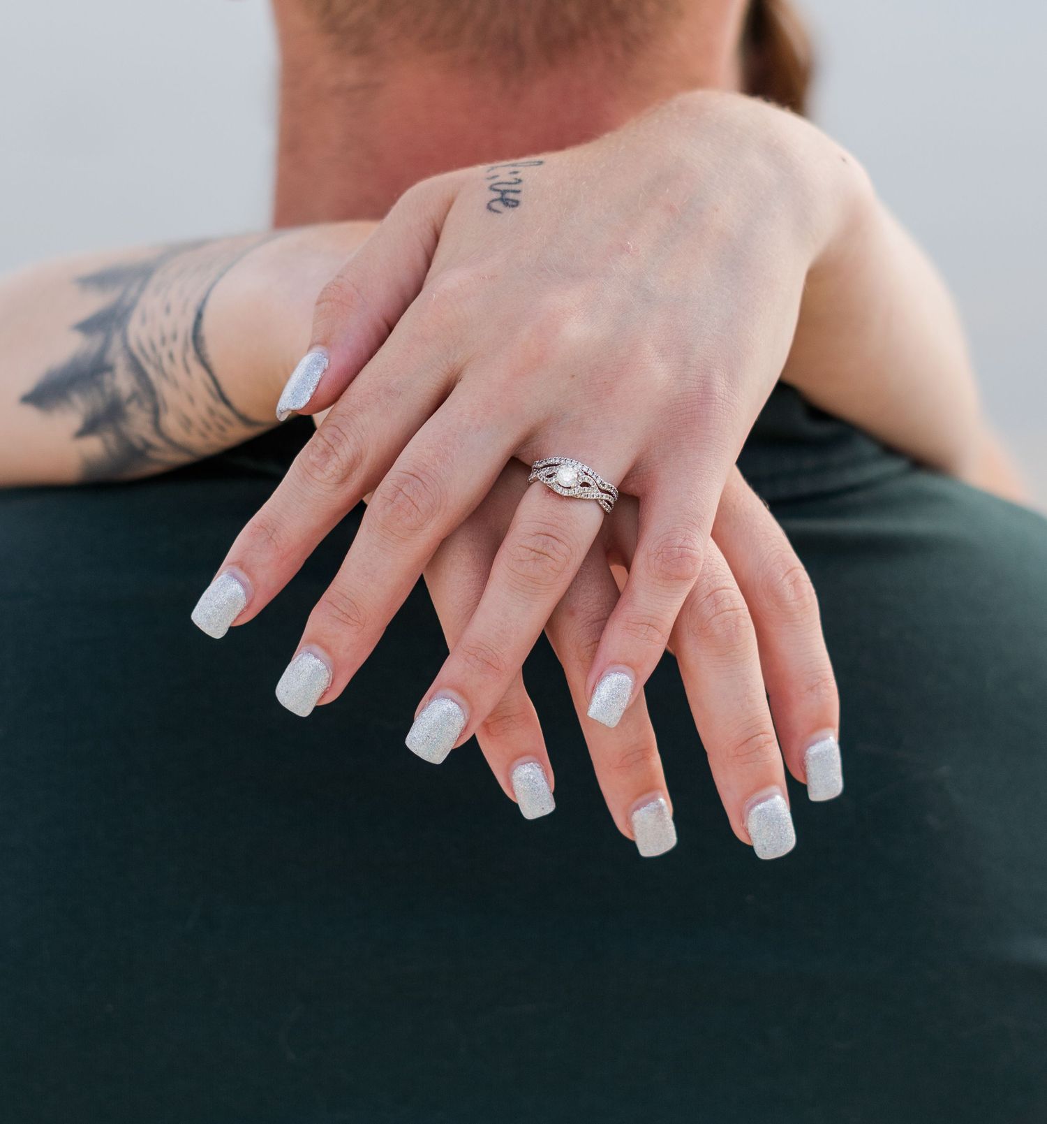 Close-up shots of hands with french manicured nails and delicate tattoos.