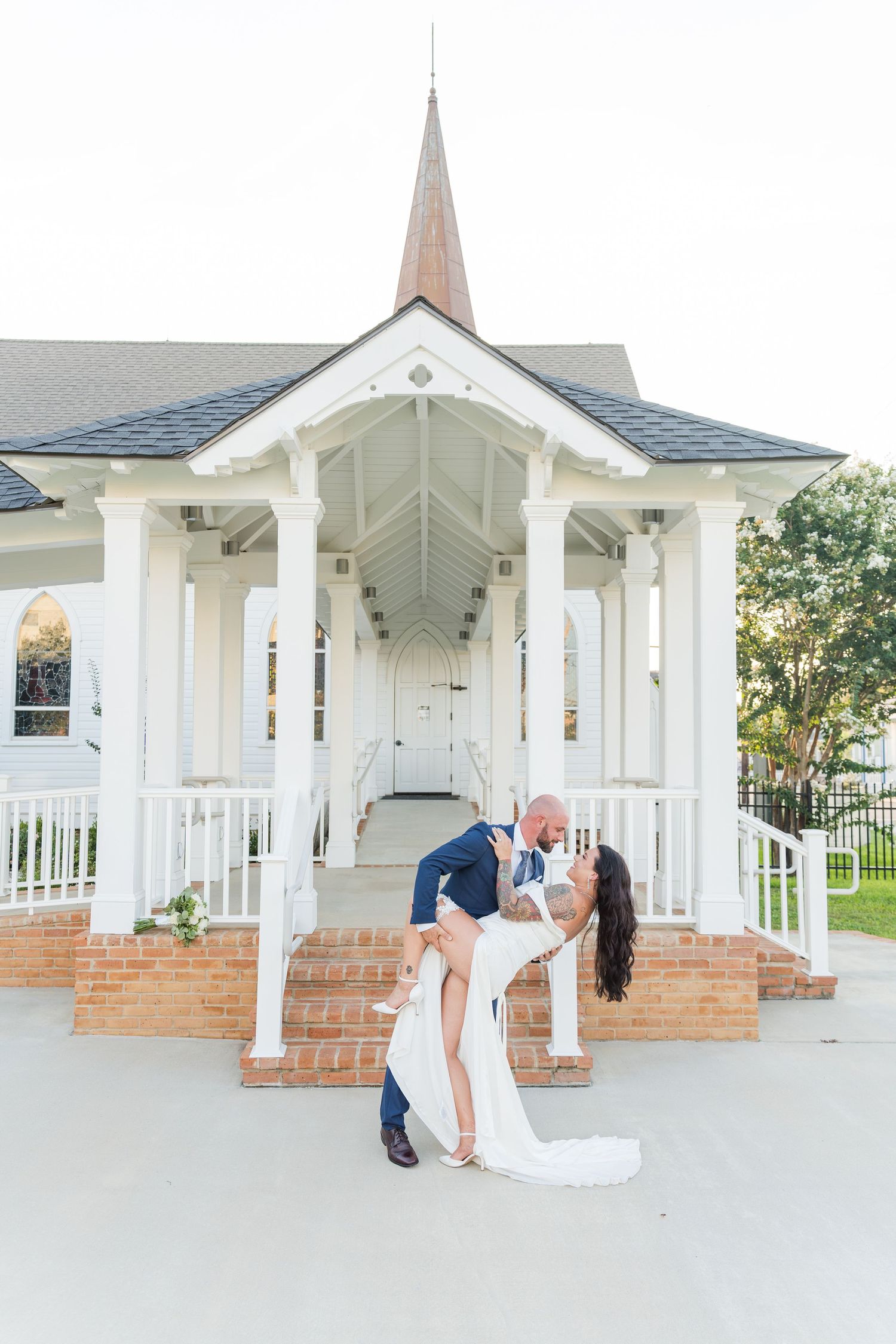 Wedding couple shares intimate moments under a white columned pavilion with brick steps.