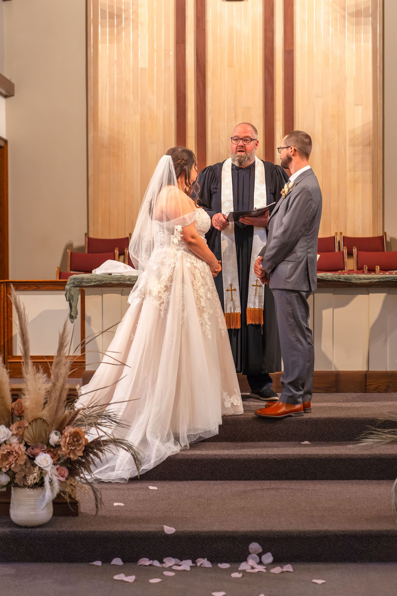 A sequence of wedding ceremony moments showing a bride and groom at the altar with rose petals scattered on the floor.
