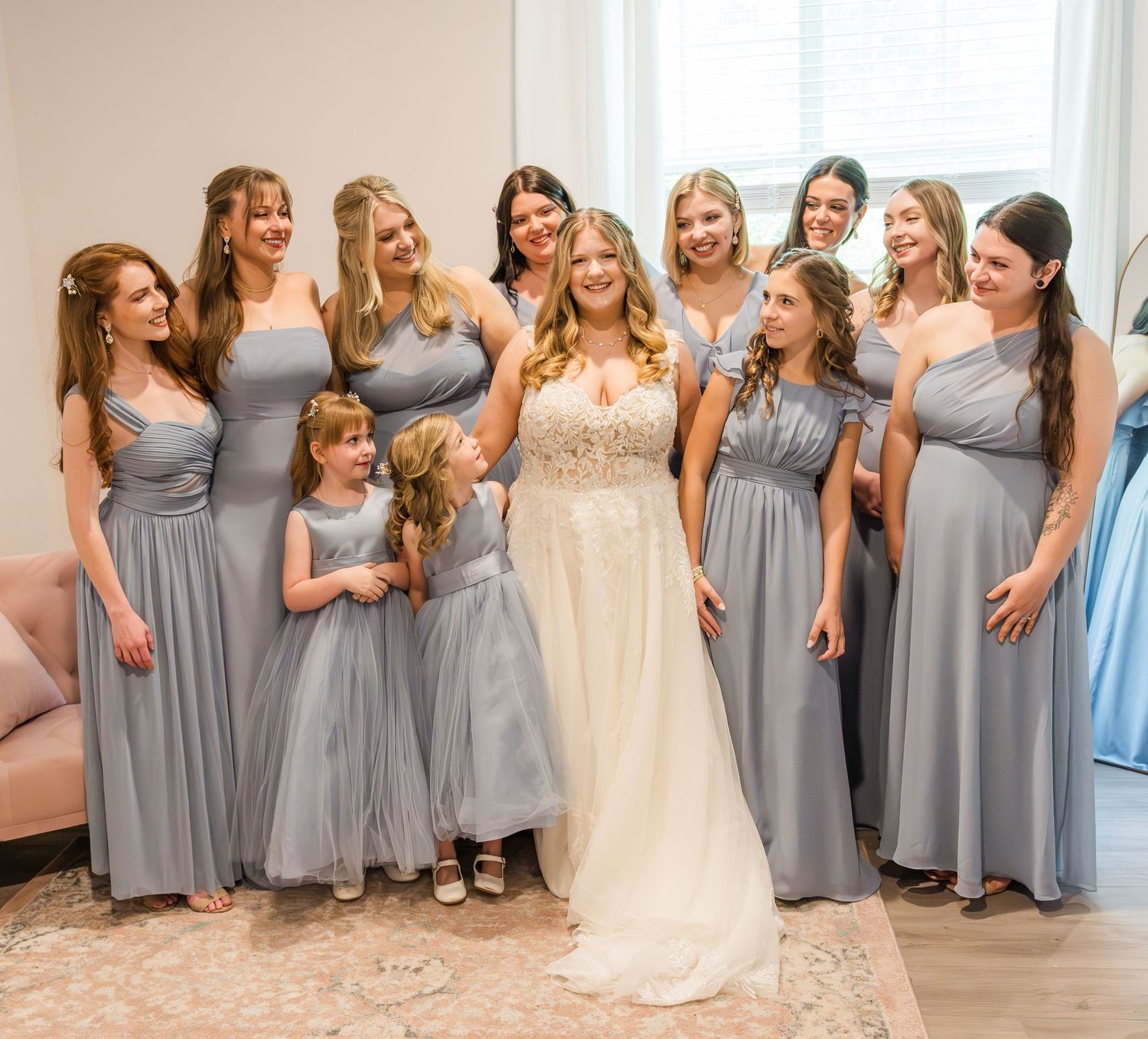 Bridesmaids in matching gray dresses pose together during wedding preparations.