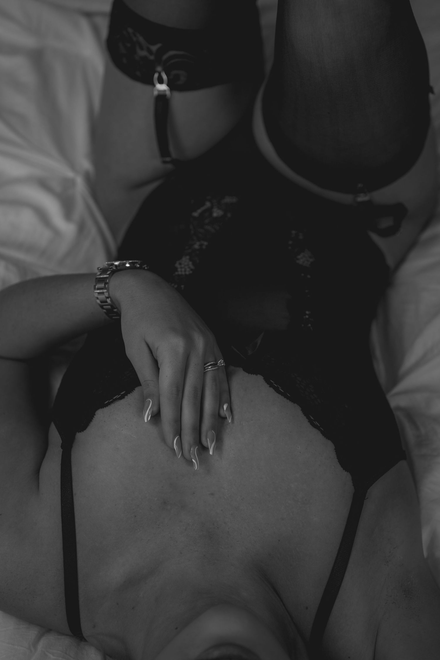 Intimate black and white photograph showing detail of rings and lace lingerie.