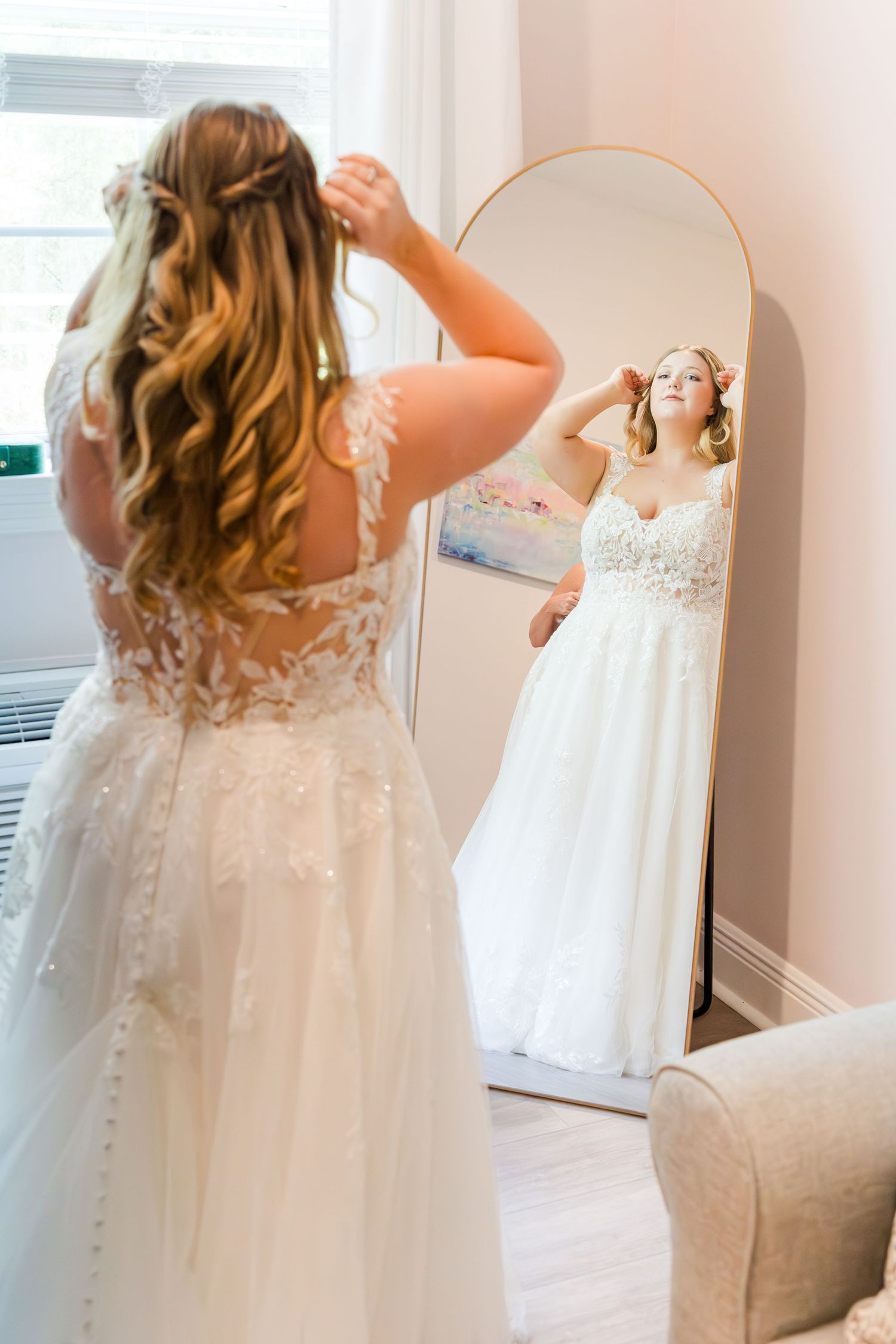 A delicate white lace wedding dress hangs in preparation for the big day.