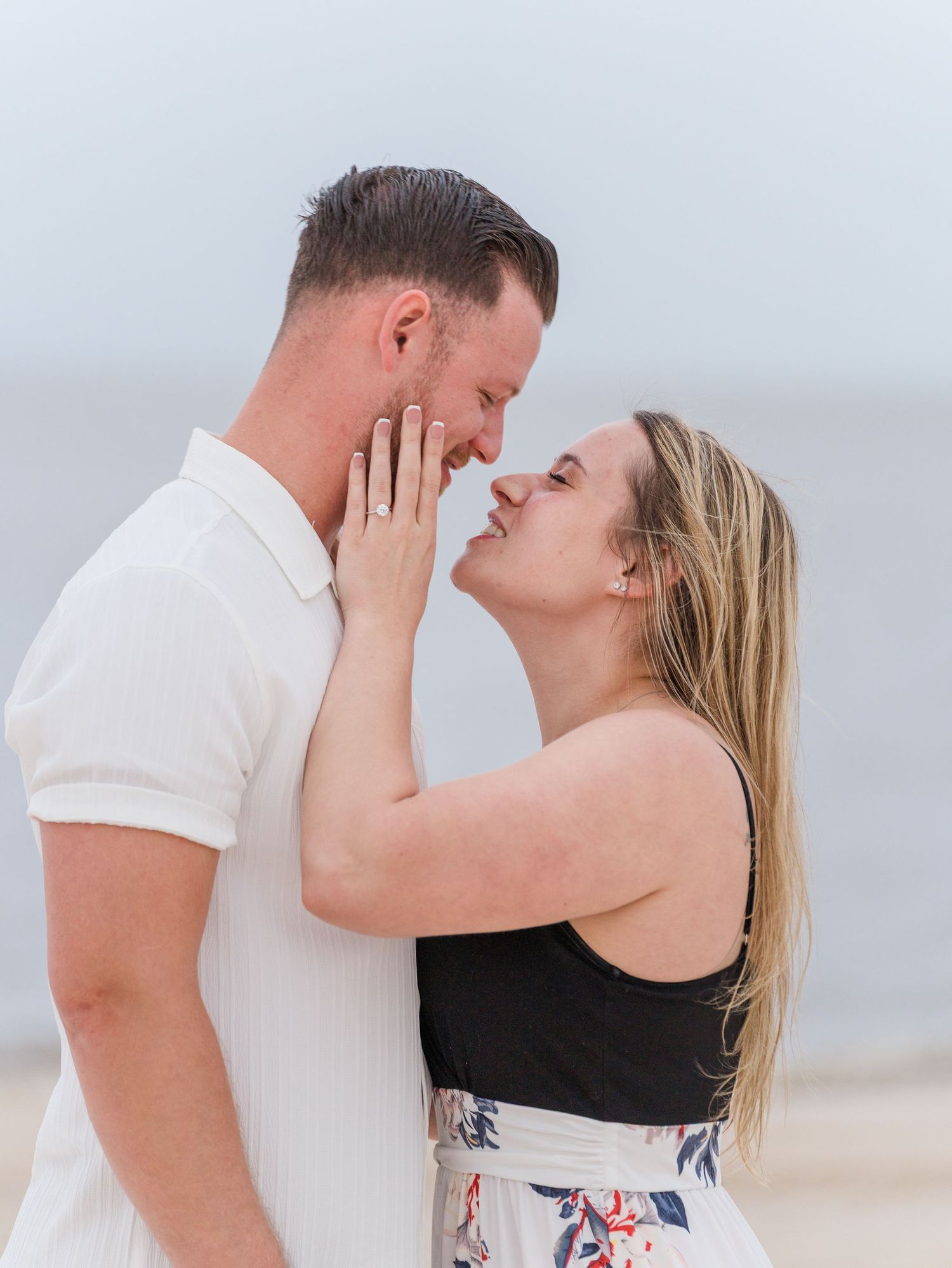 Intimate moment between couple during beach photoshoot at sunset.