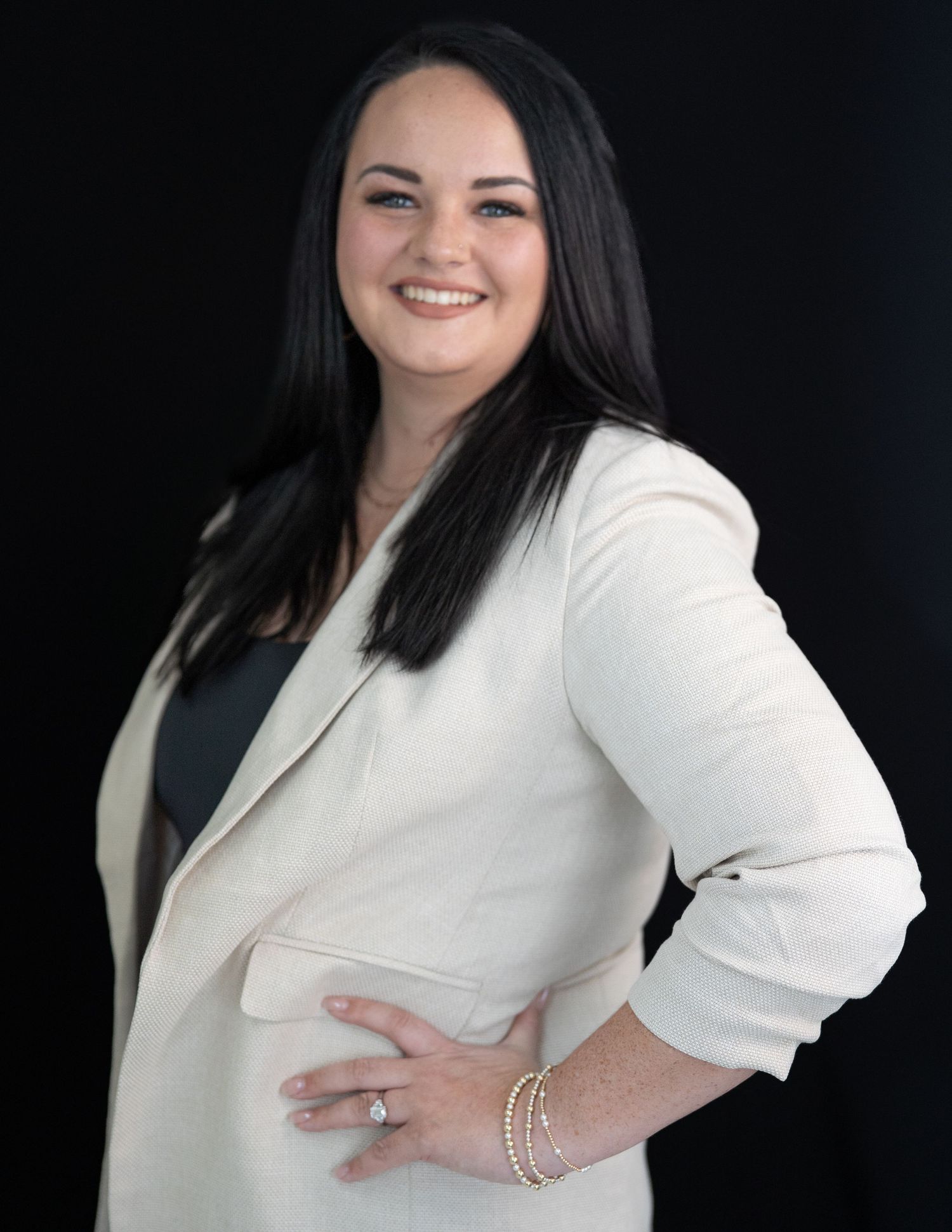 Professional studio portraits in white blazer against black background.