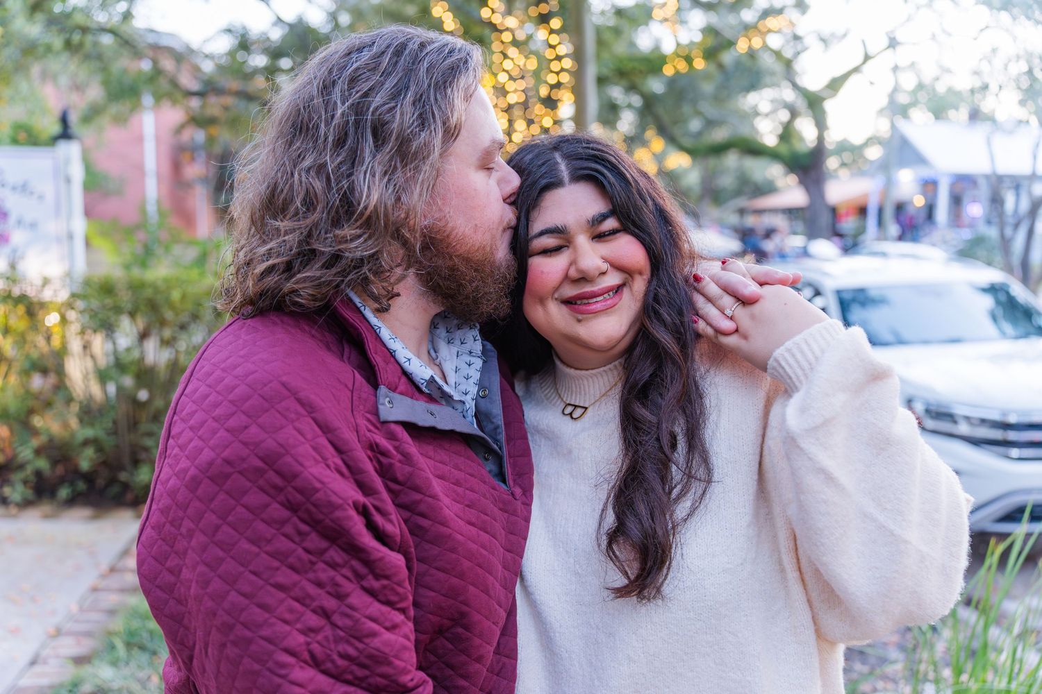 Two people in autumn attire share a joyful moment while walking outdoors on a sunny day.