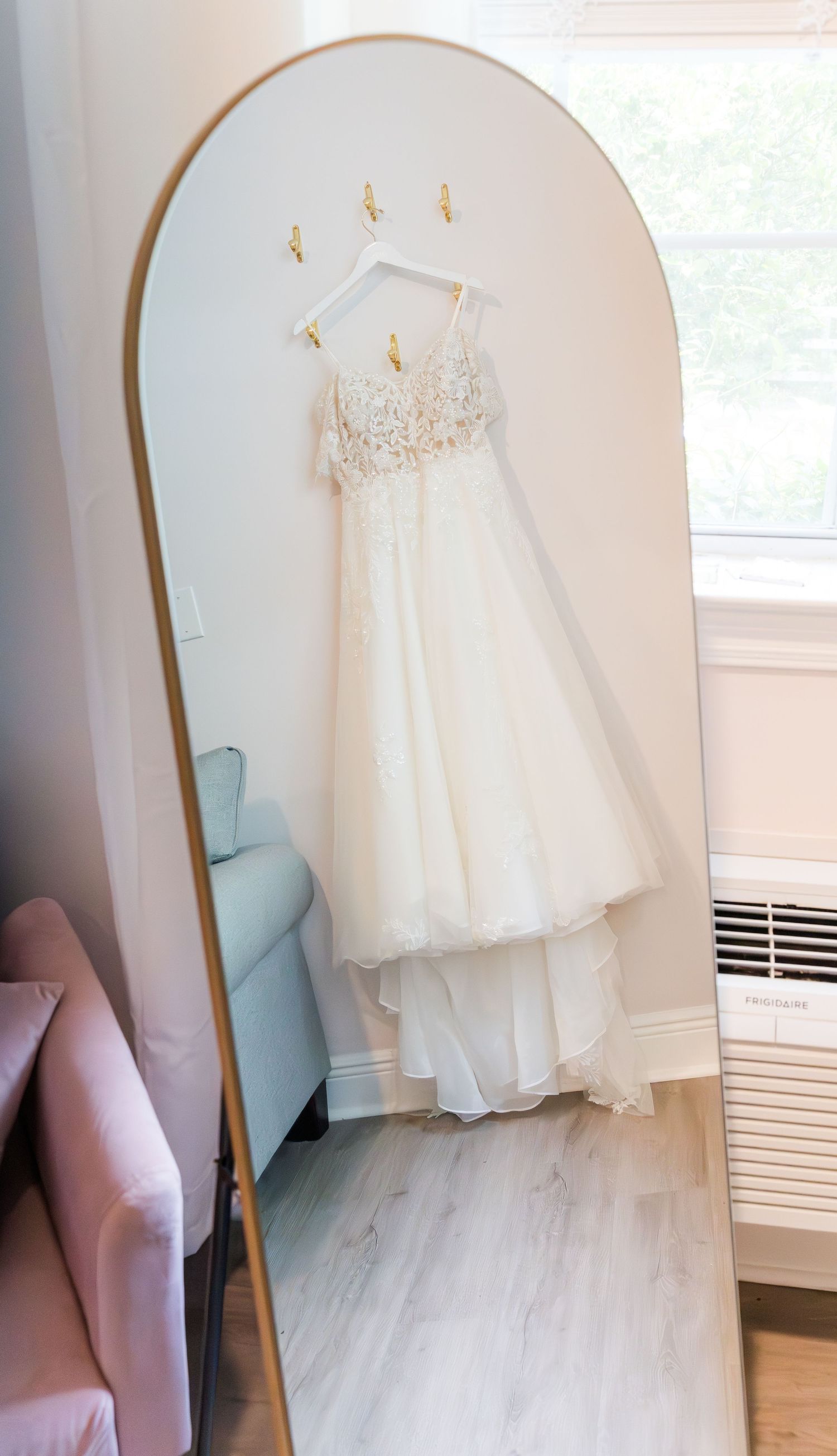 A white wedding dress hangs elegantly on display in a bright room.