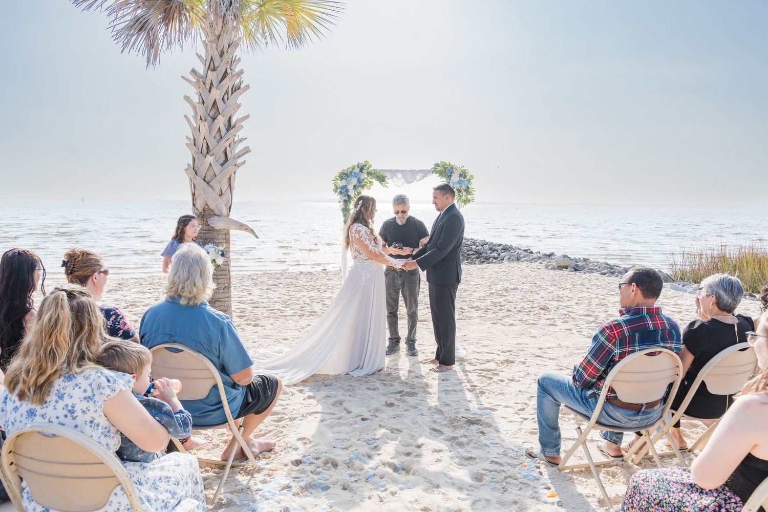 People sitting in beach chairs watching a beautiful sunset over white sandy beach in Florida.
