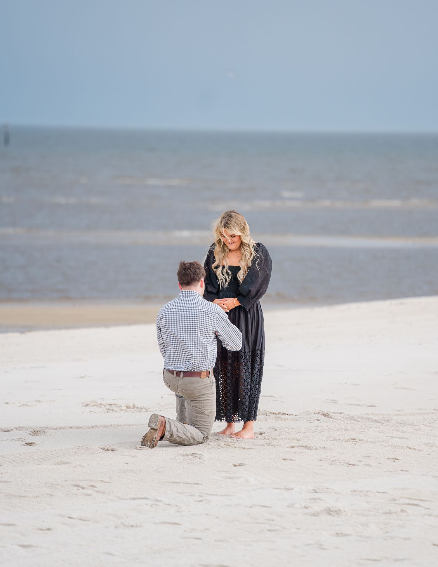 Beach proposal sequence showing couple getting engaged on white sandy shore.