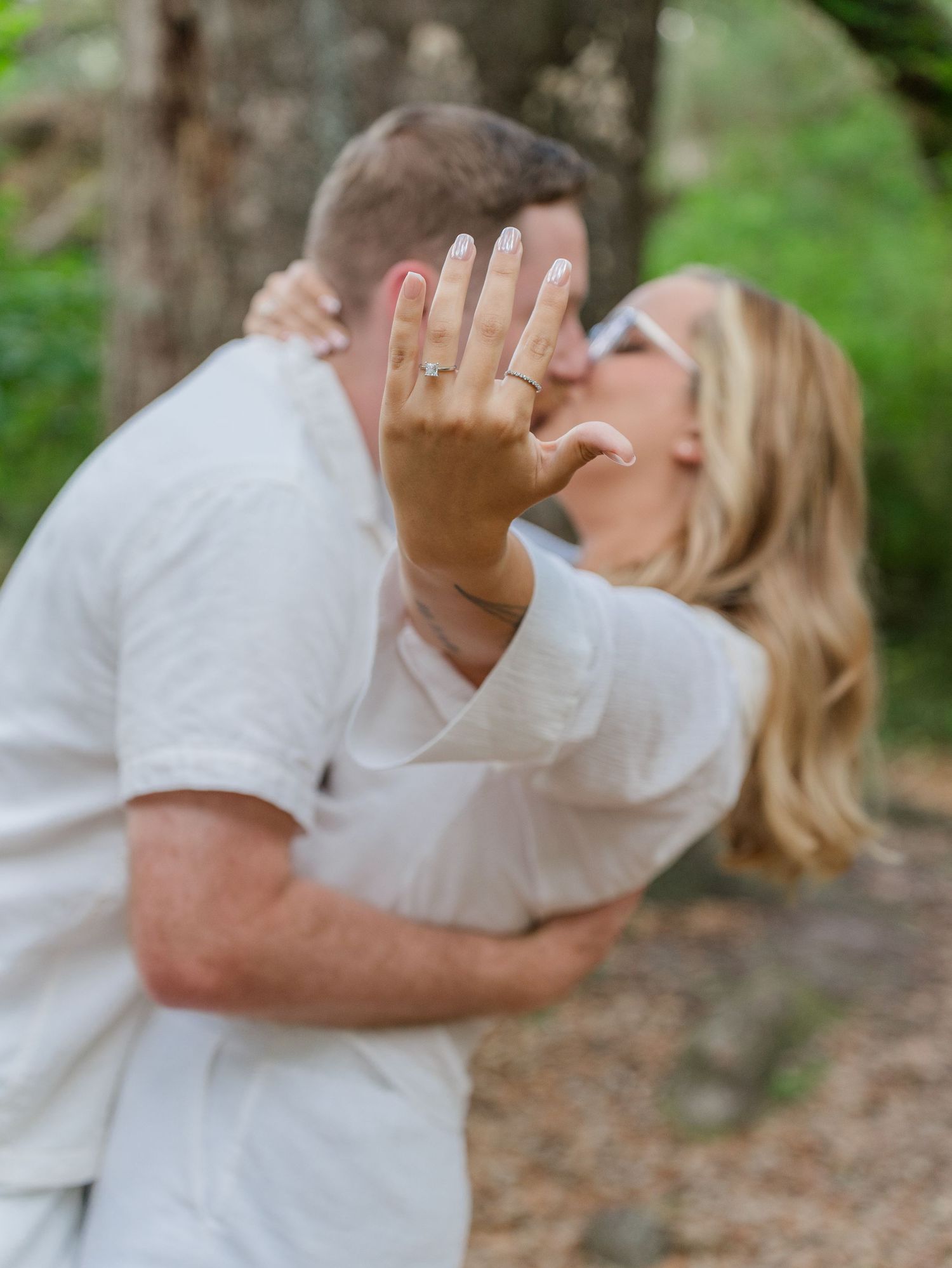 Romantic couple sharing a kiss in a lush green garden setting.