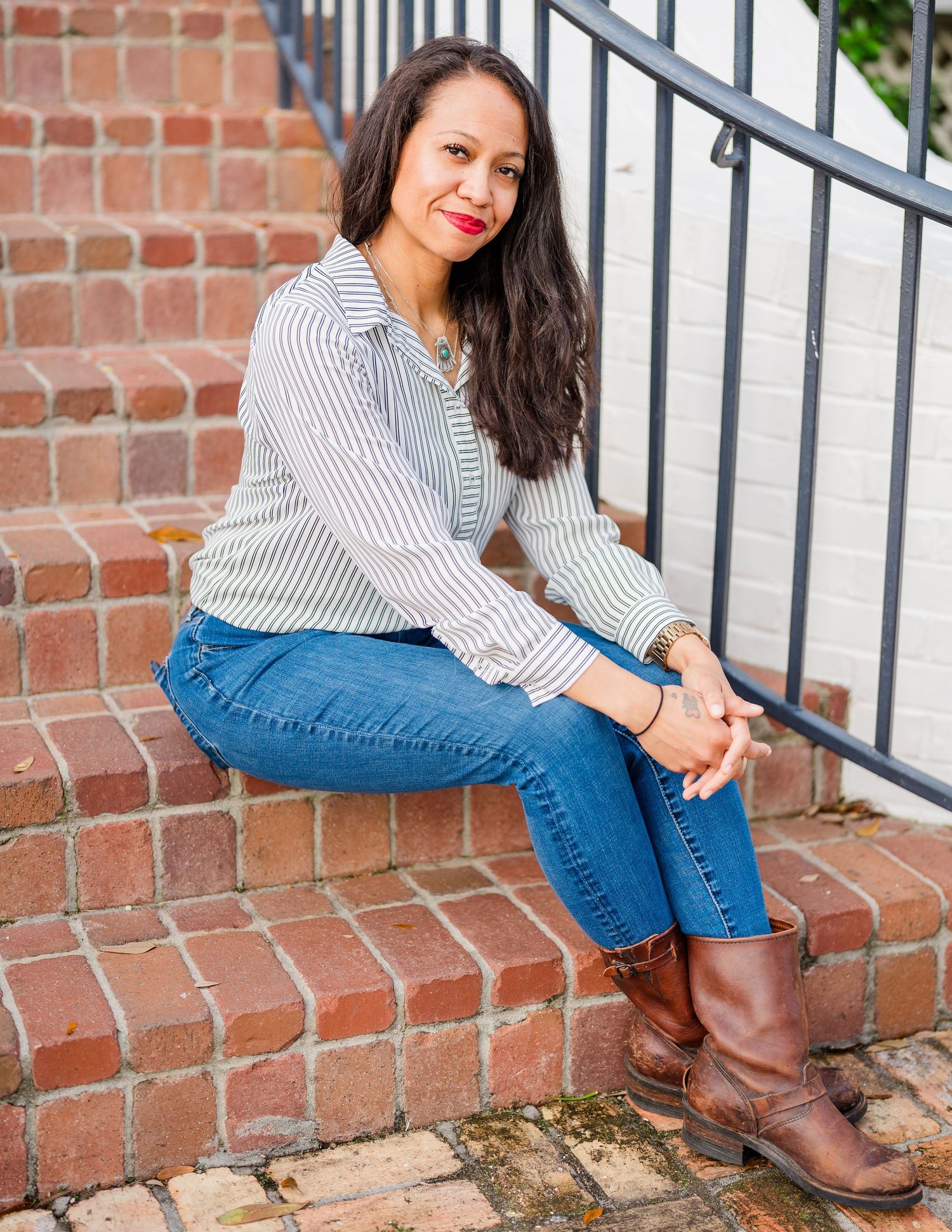 Casual portraits on brick steps wearing striped shirt and brown boots.