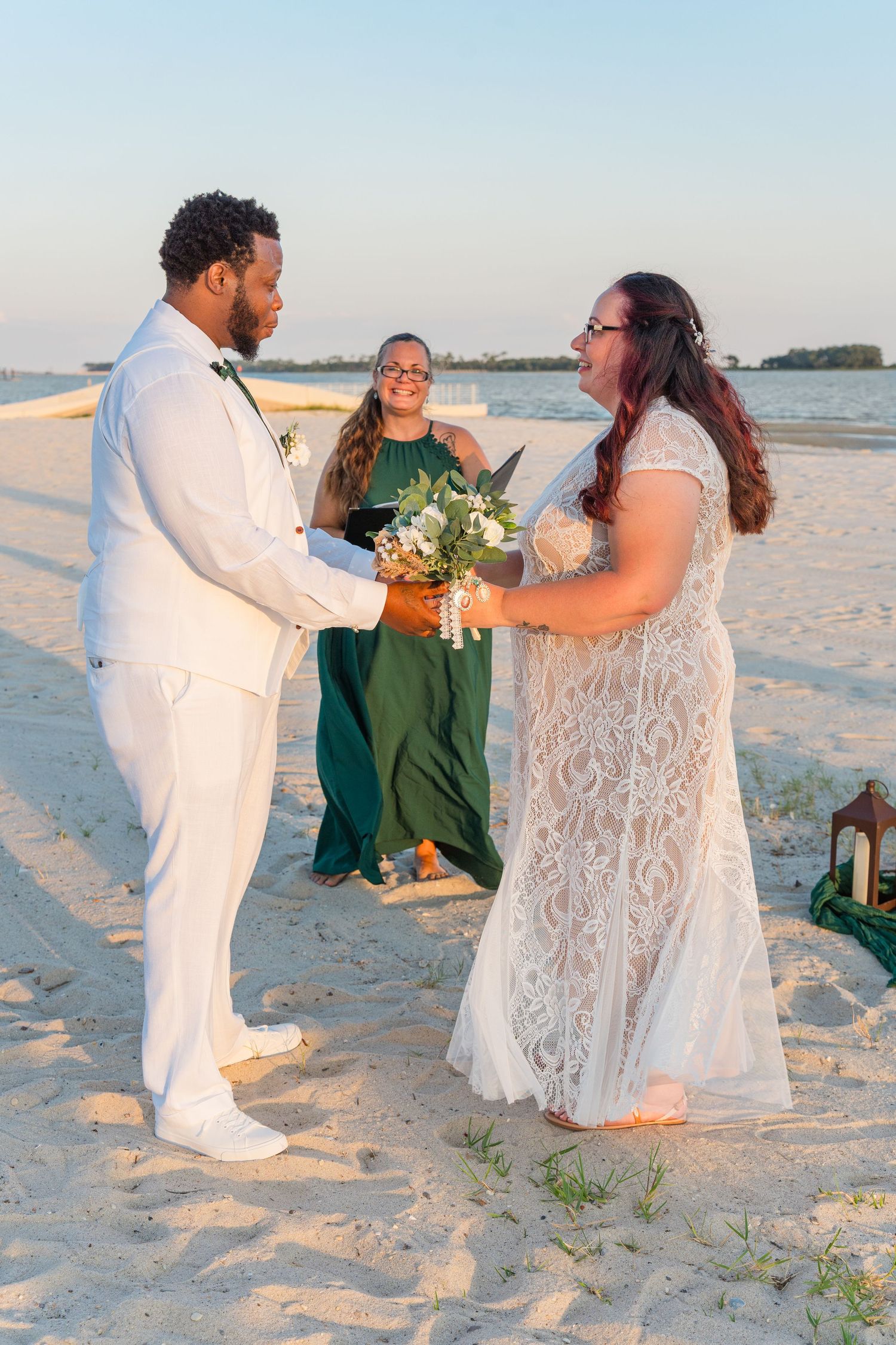 Beach wedding ceremony with officiant and couple exchanging vows on sandy shore.