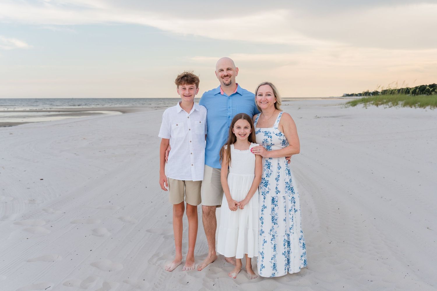 Multi-generational family portrait session on a serene beach at sunset.