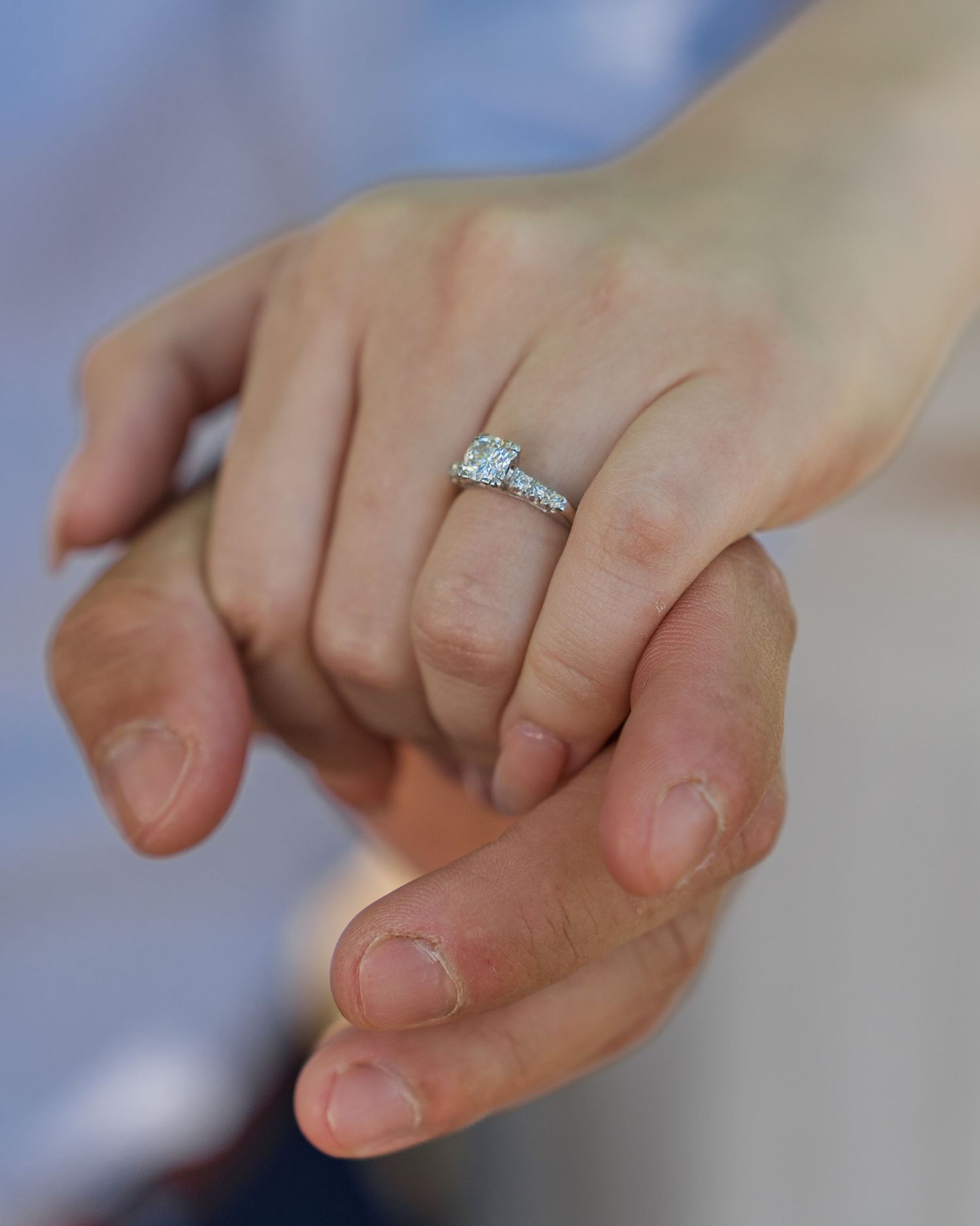 Close up view of hands with an engagement ring sparkling in sunlight.