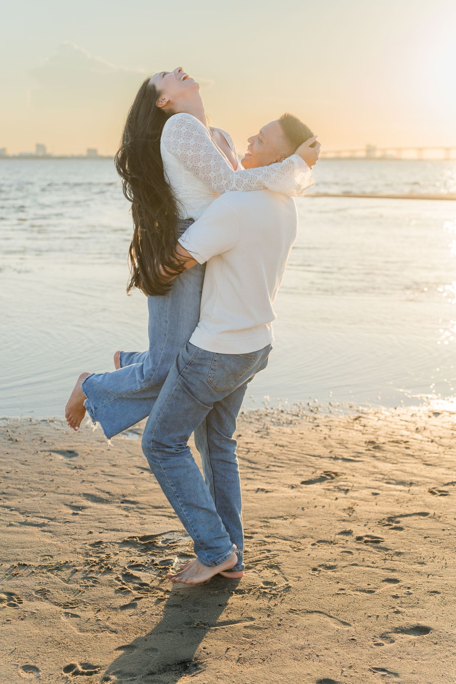 Playful couple sharing romantic moment on beach at sunset.