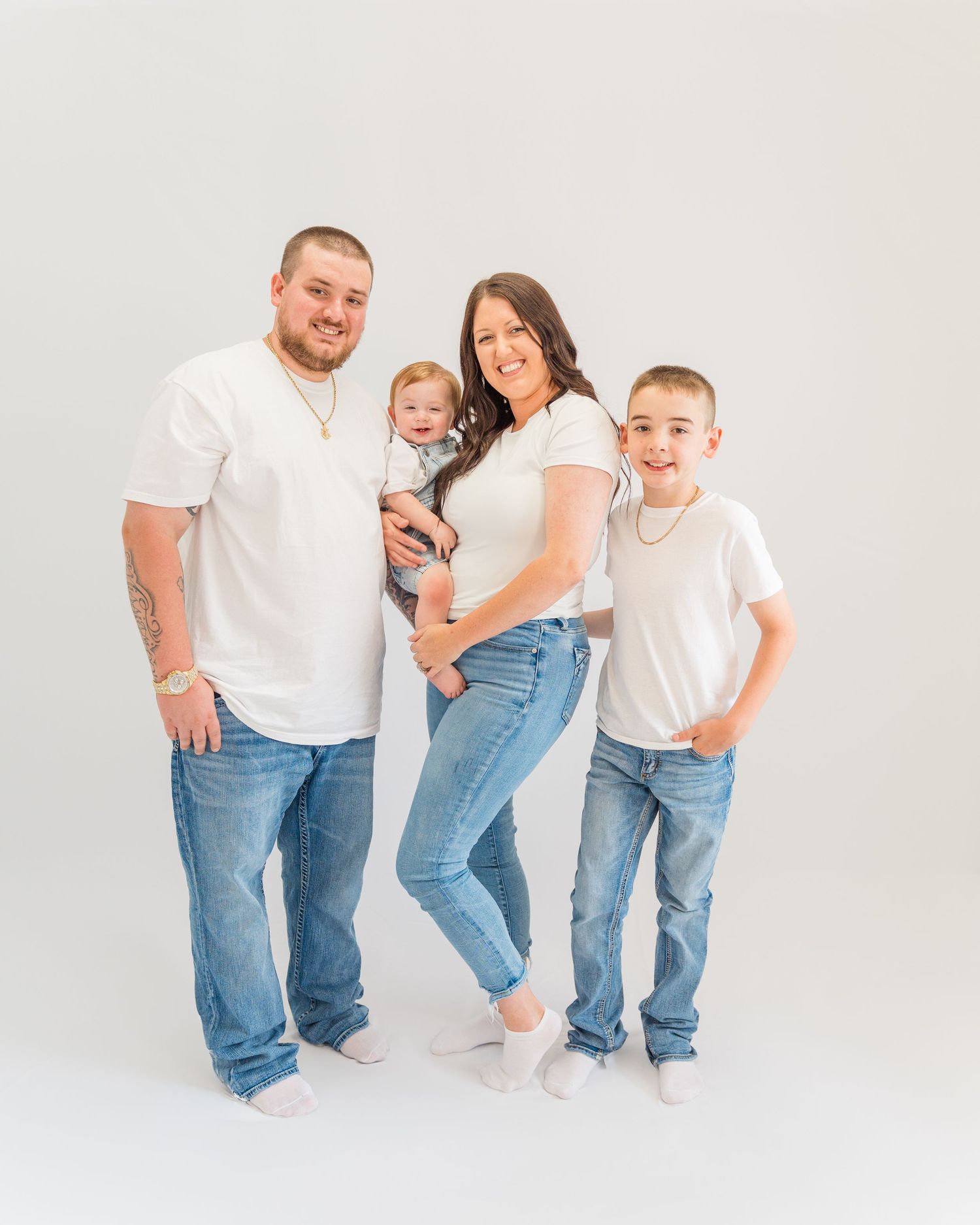 Casual family photo session in a bright white studio with matching outfits.