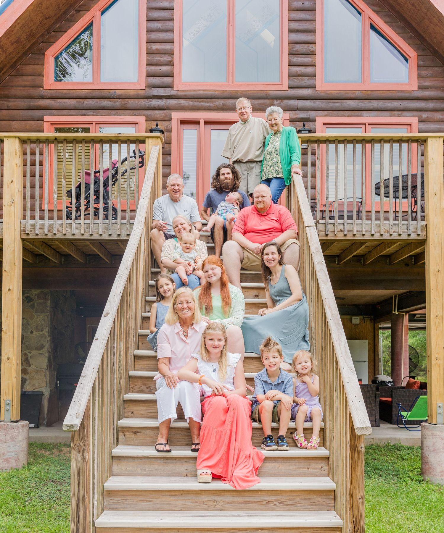 Multi-generational family gathered on wooden stairs of a rustic cabin.