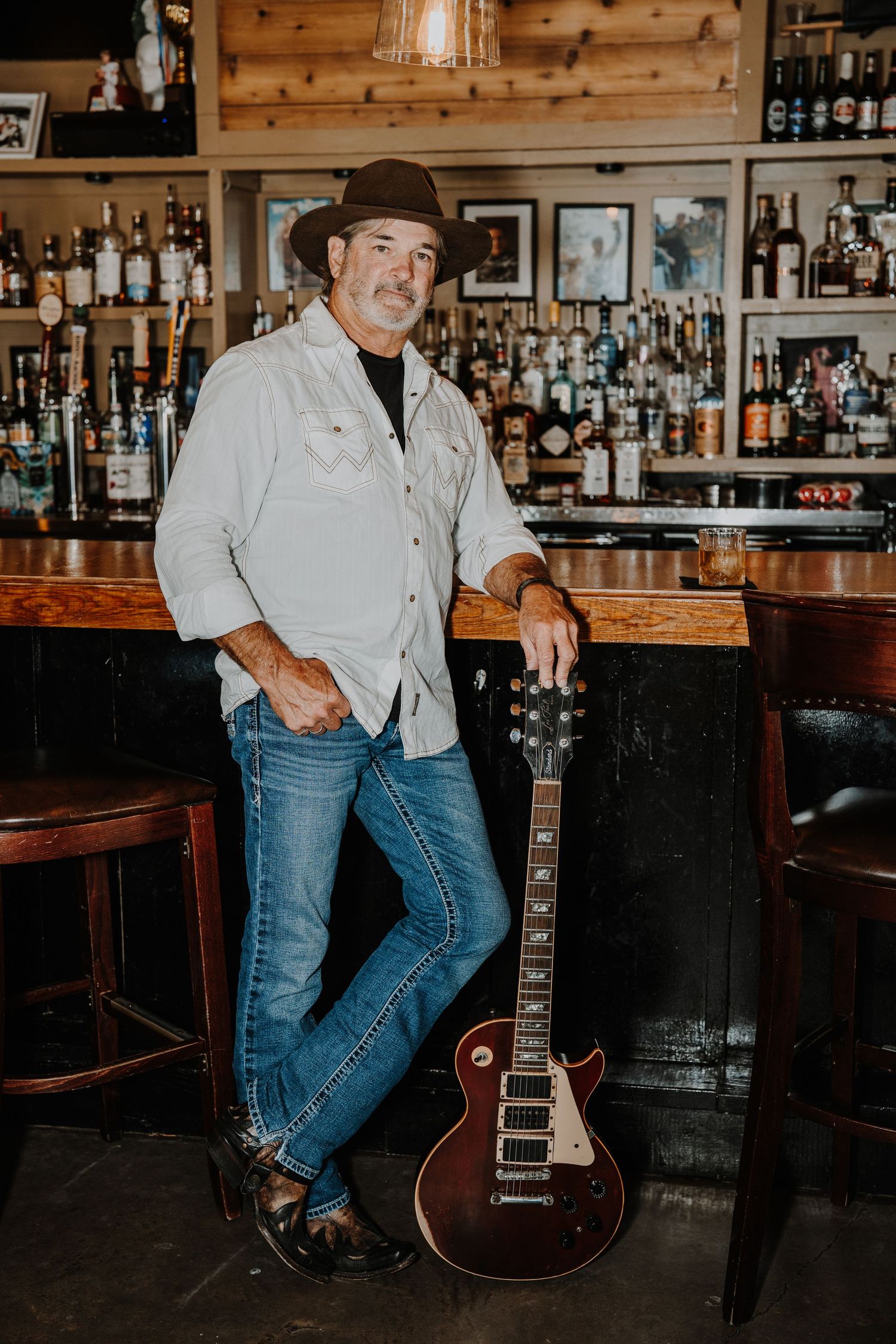 Bar interior with wooden decor and electric guitar against rustic backdrop.