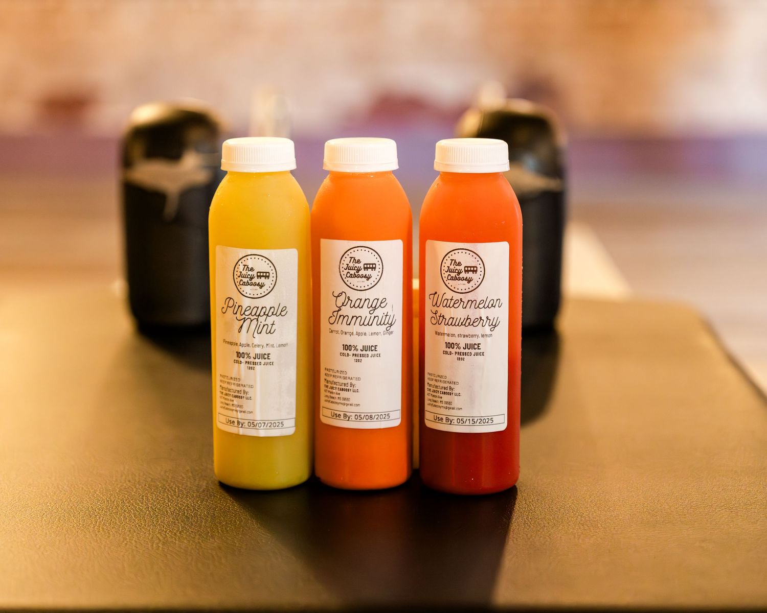 Collection of orange, yellow and red bottled drinks displayed on a wooden surface.