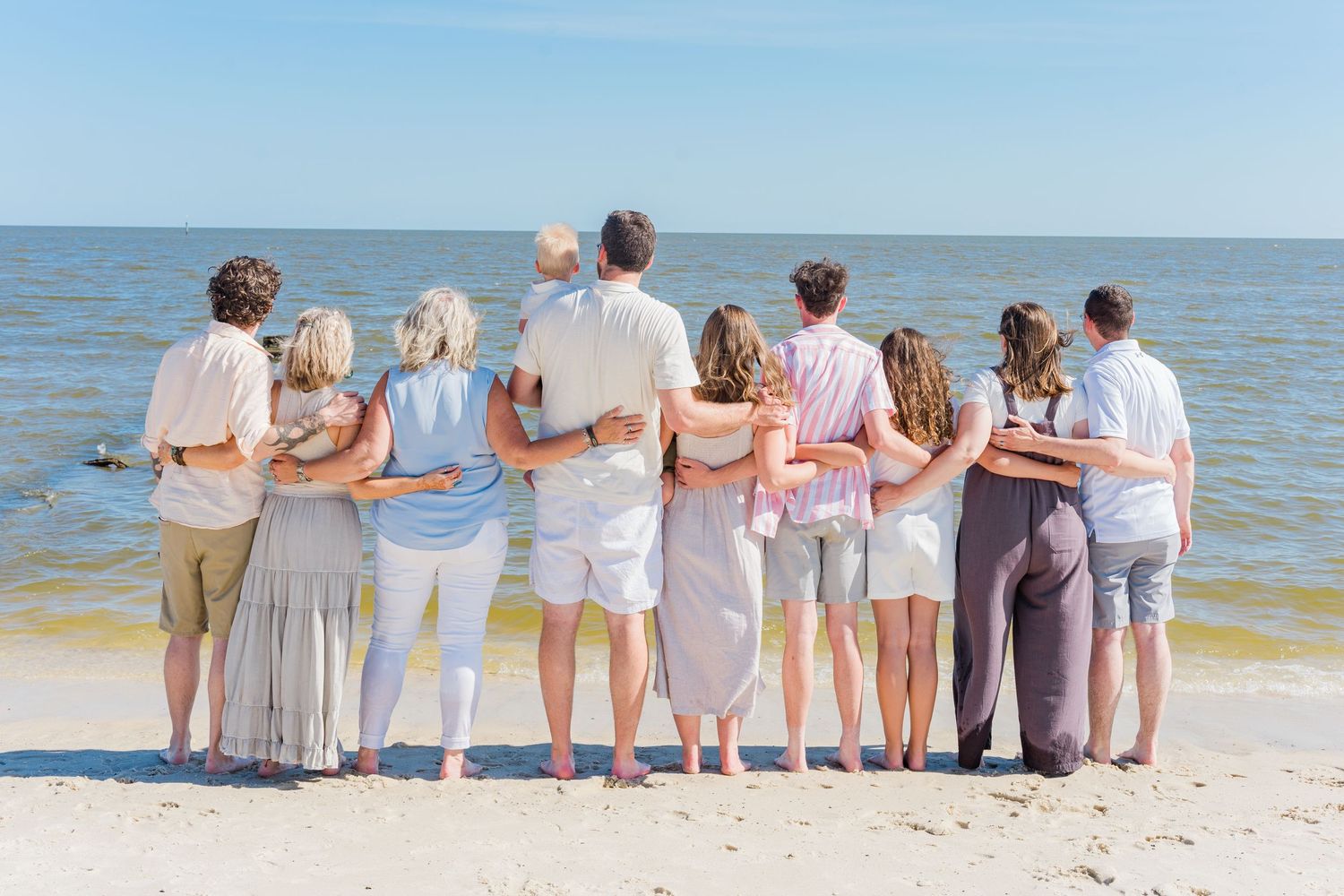 Group of people standing with their backs to camera looking out at ocean view.