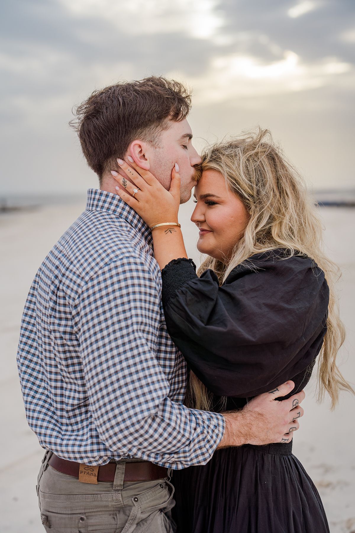 Romantic sunset engagement photos on beach with couple in casual attire.