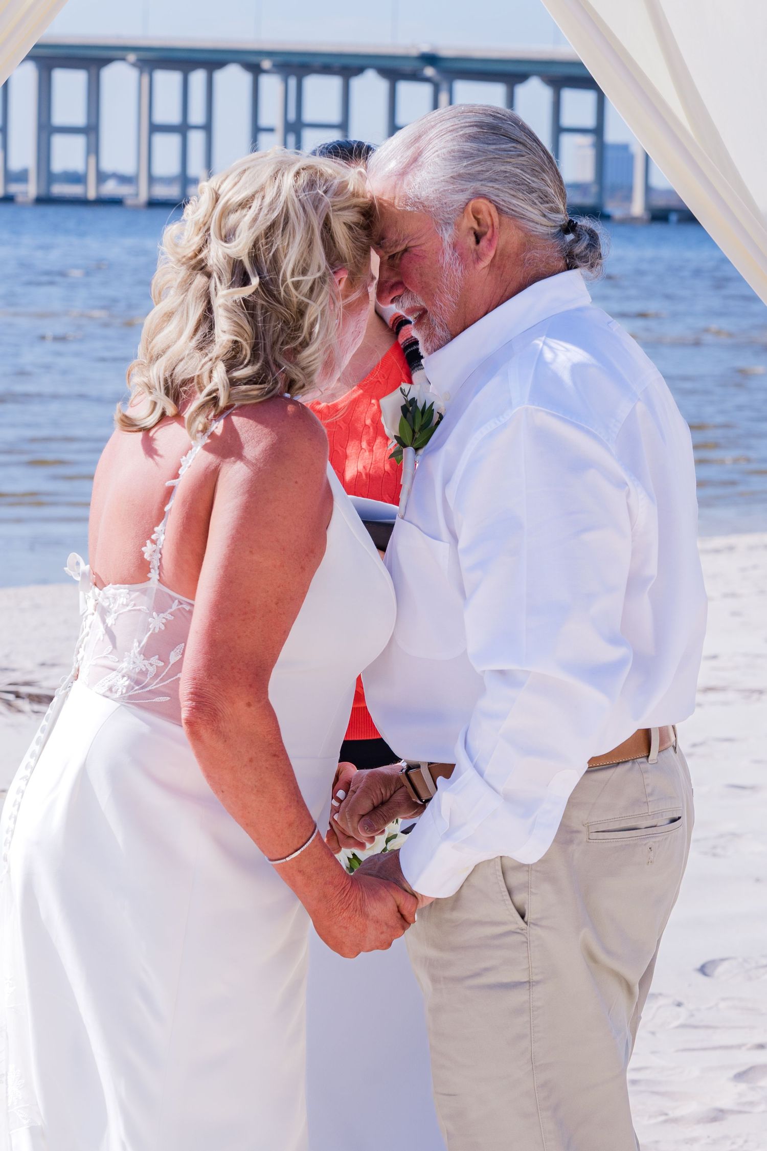 A romantic beach wedding sequence shows a couple in white embracing and sharing a kiss by the ocean.