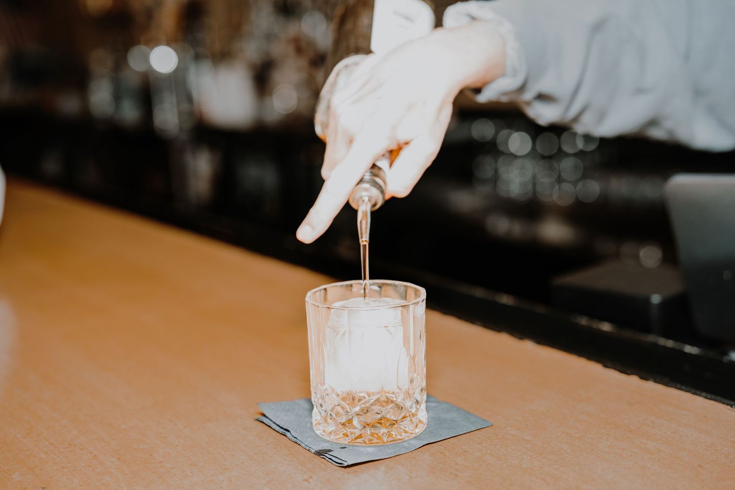 Row of elegant cocktail glasses filled with white drinks on dark bar counter.