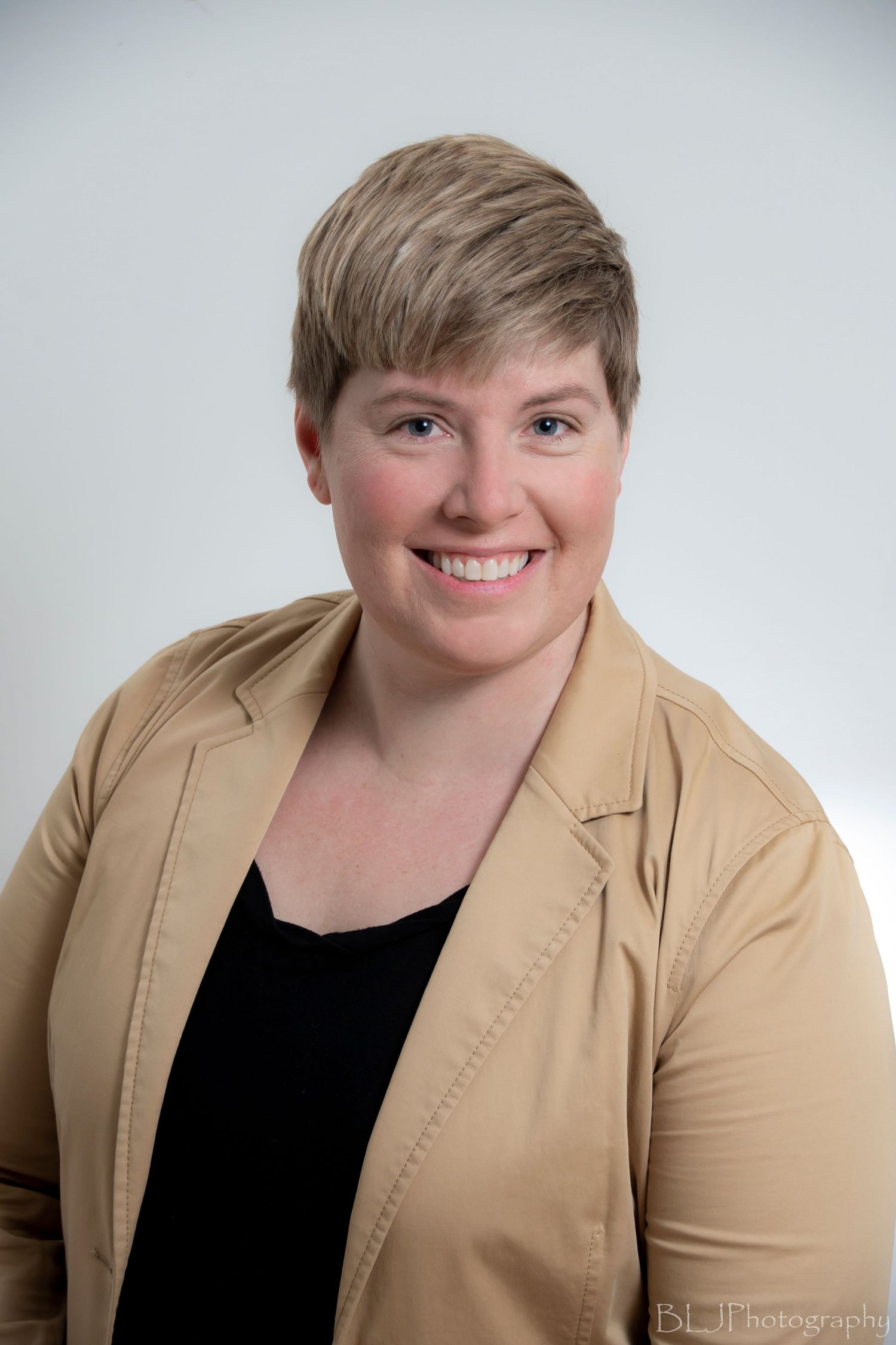 Portrait of a woman with short hair and tan blazer on white background