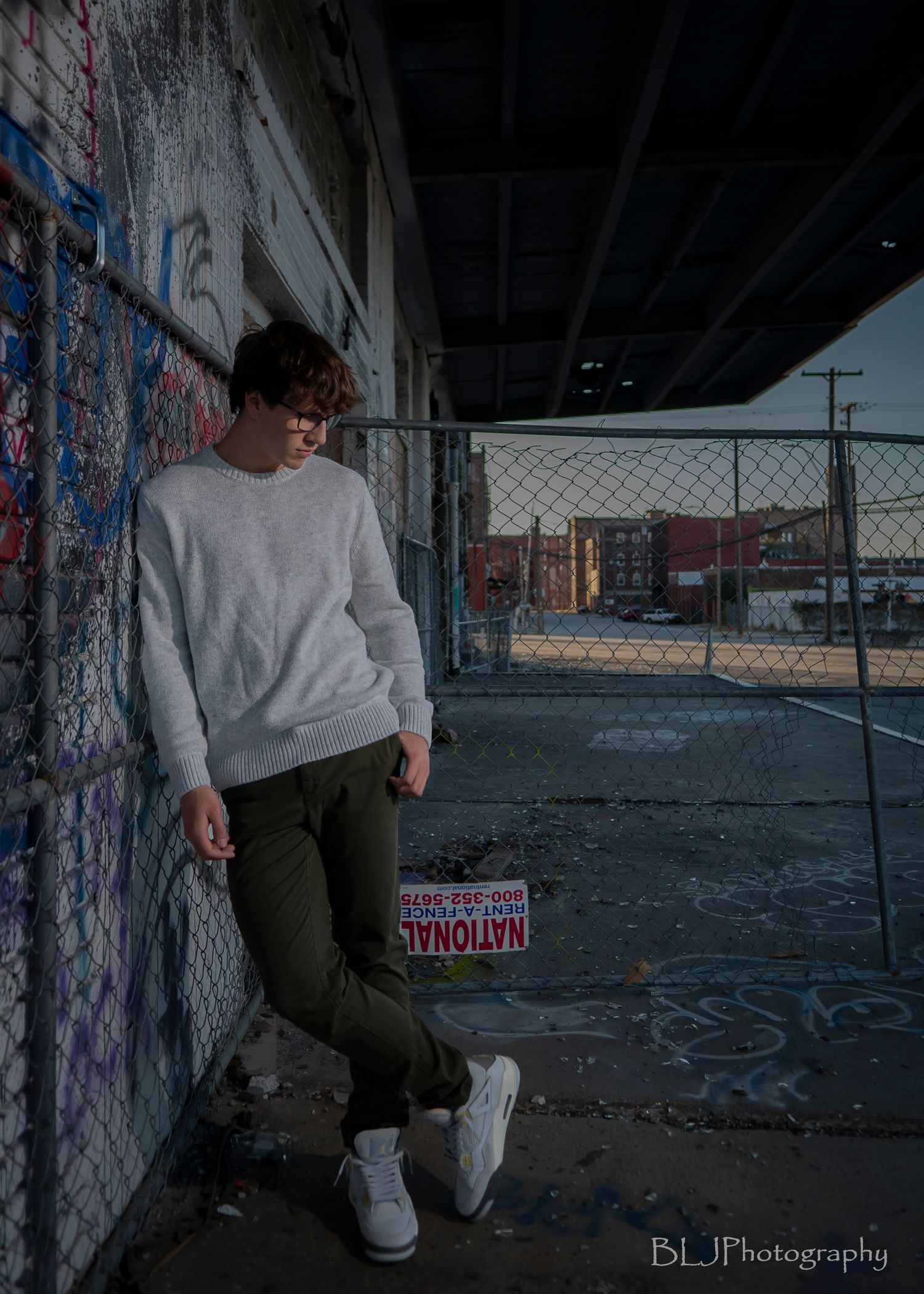 Senior portraits/West Bottoms/ boy with moody lighting looking down and a graffiti wall