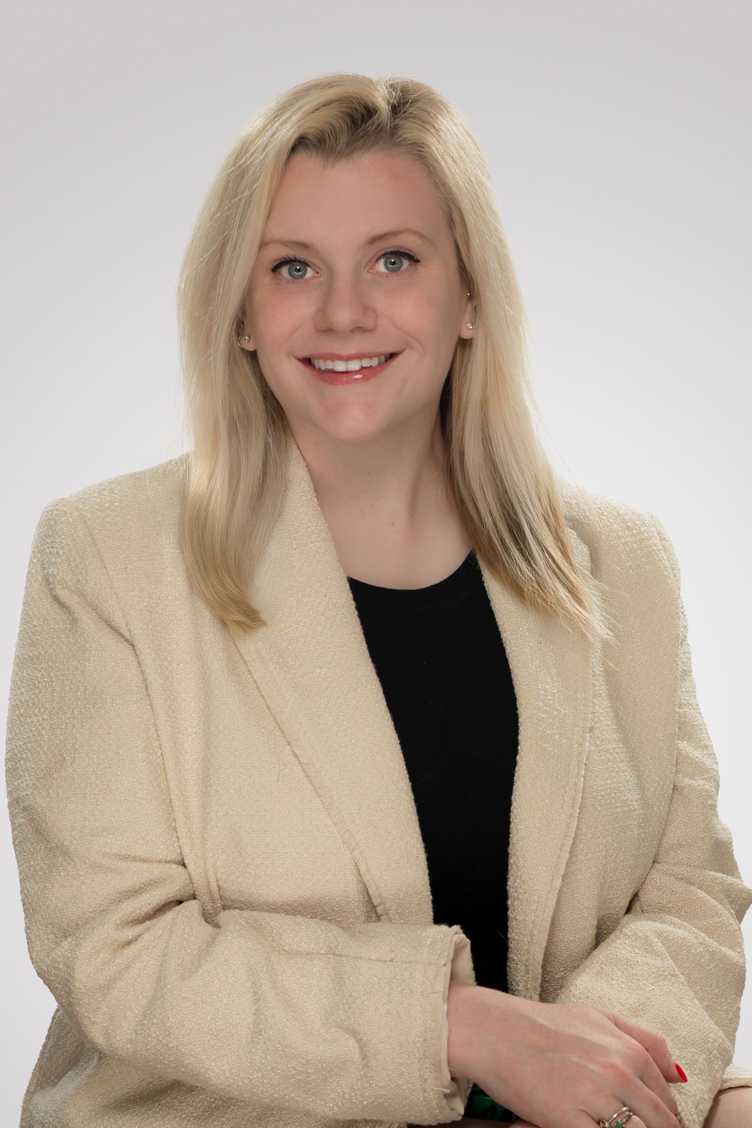 Business Portrait of a real estate agent with blond hair, a cream blazer and black shirt on a white background