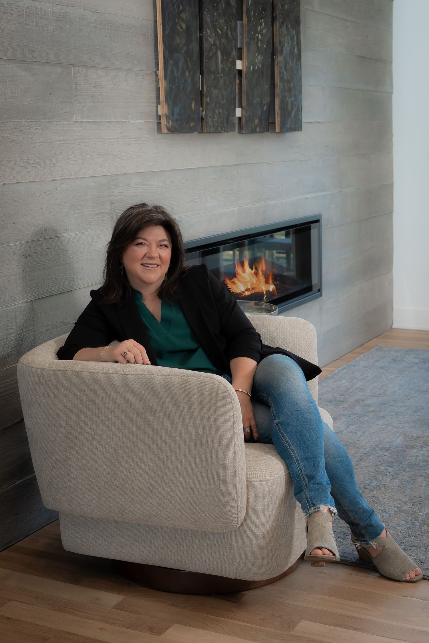 Business portrait of a real estate agent sitting on a cream chair in front of a fireplace