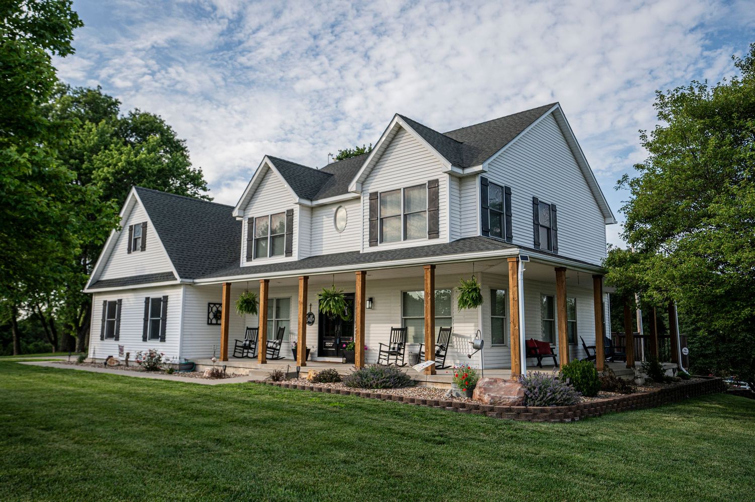 a white house with a wrap around porch and blue skies