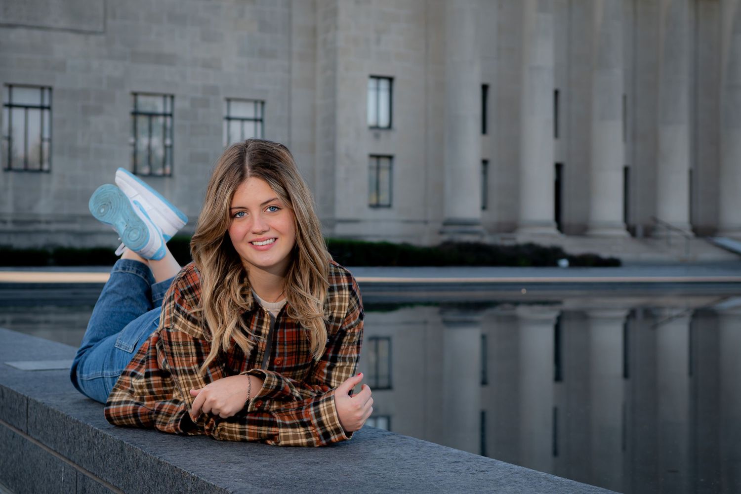 High school senior portraits/ The Nelson Atkins Museum/ girl on tummy with feet kicked up and a pond reflecting pillars