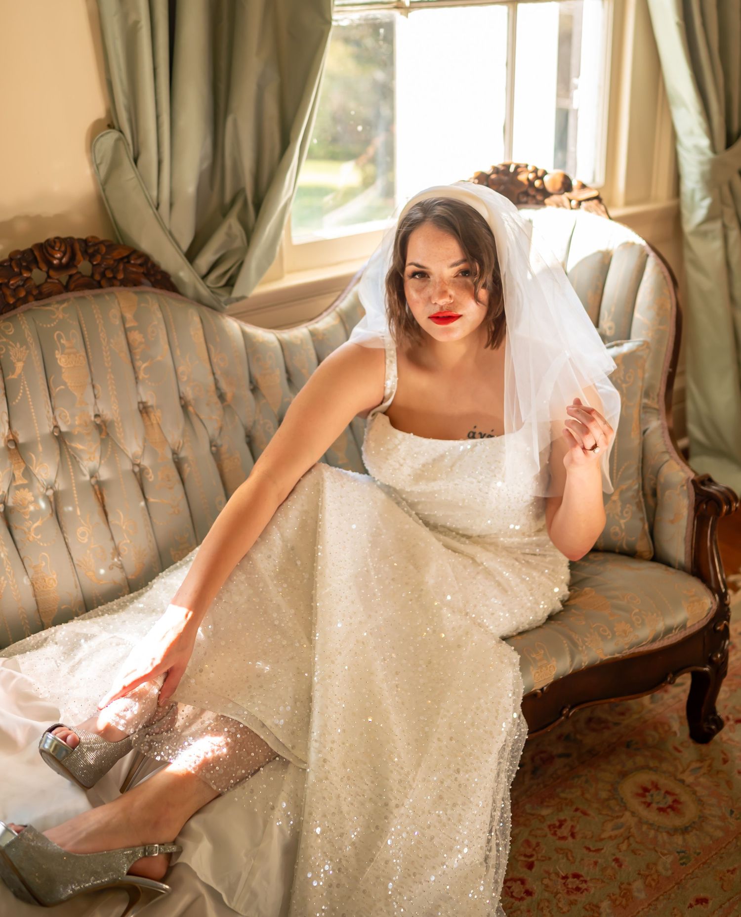 A person in a sparkling white dress poses on an elegant vintage sofa in various elegant positions.