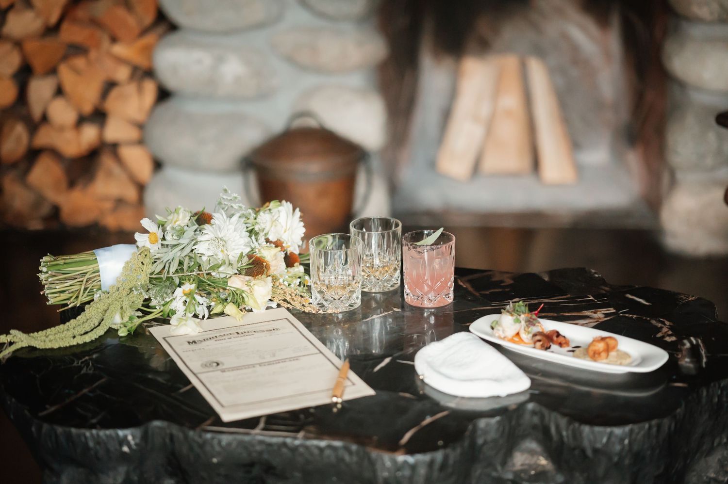 Rustic wedding reception table settings with woodpile and candlelit decor.