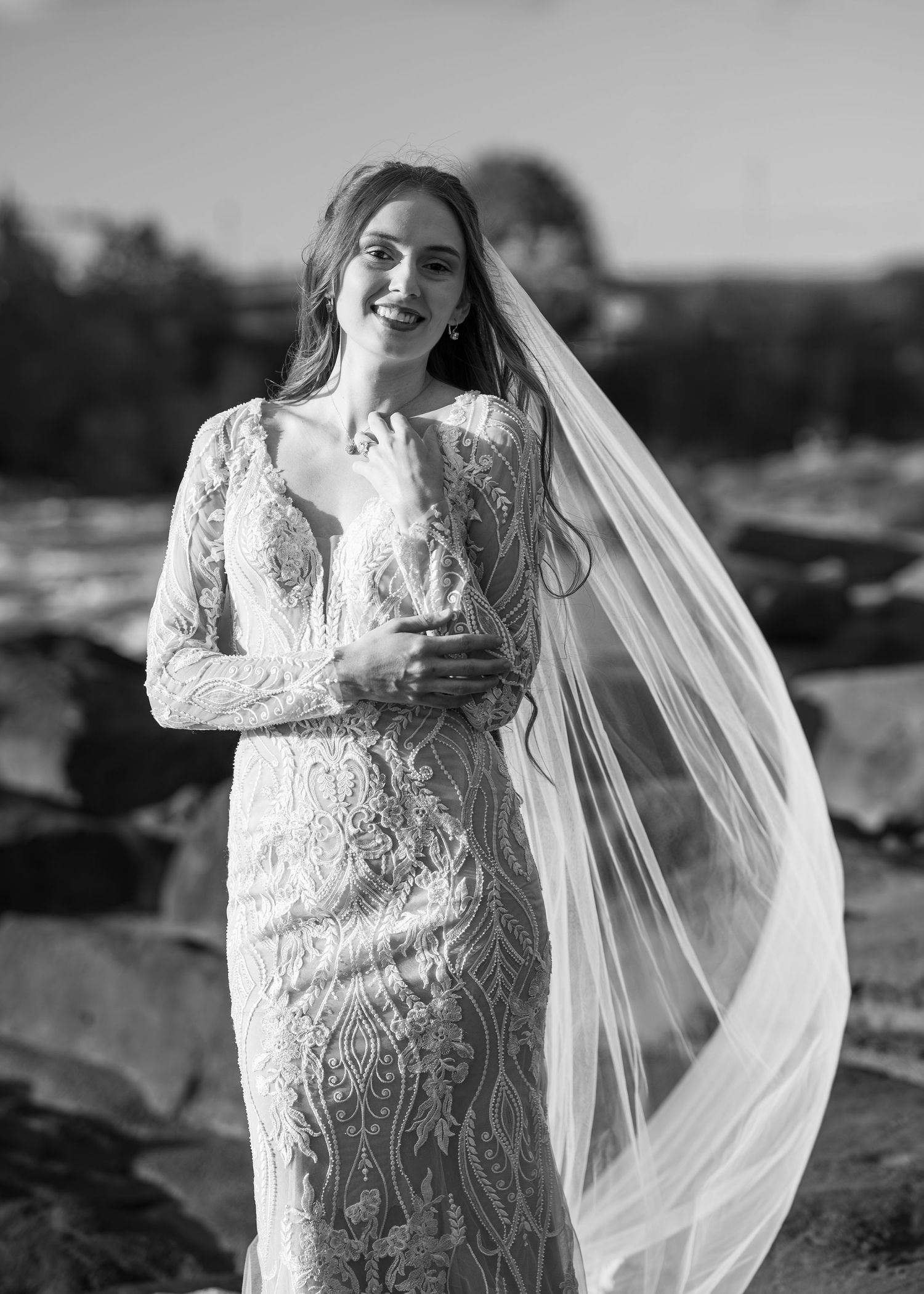 A stunning bridal photoshoot featuring an elegant lace wedding gown and flowing veil against a dramatic black and white backdrop.
