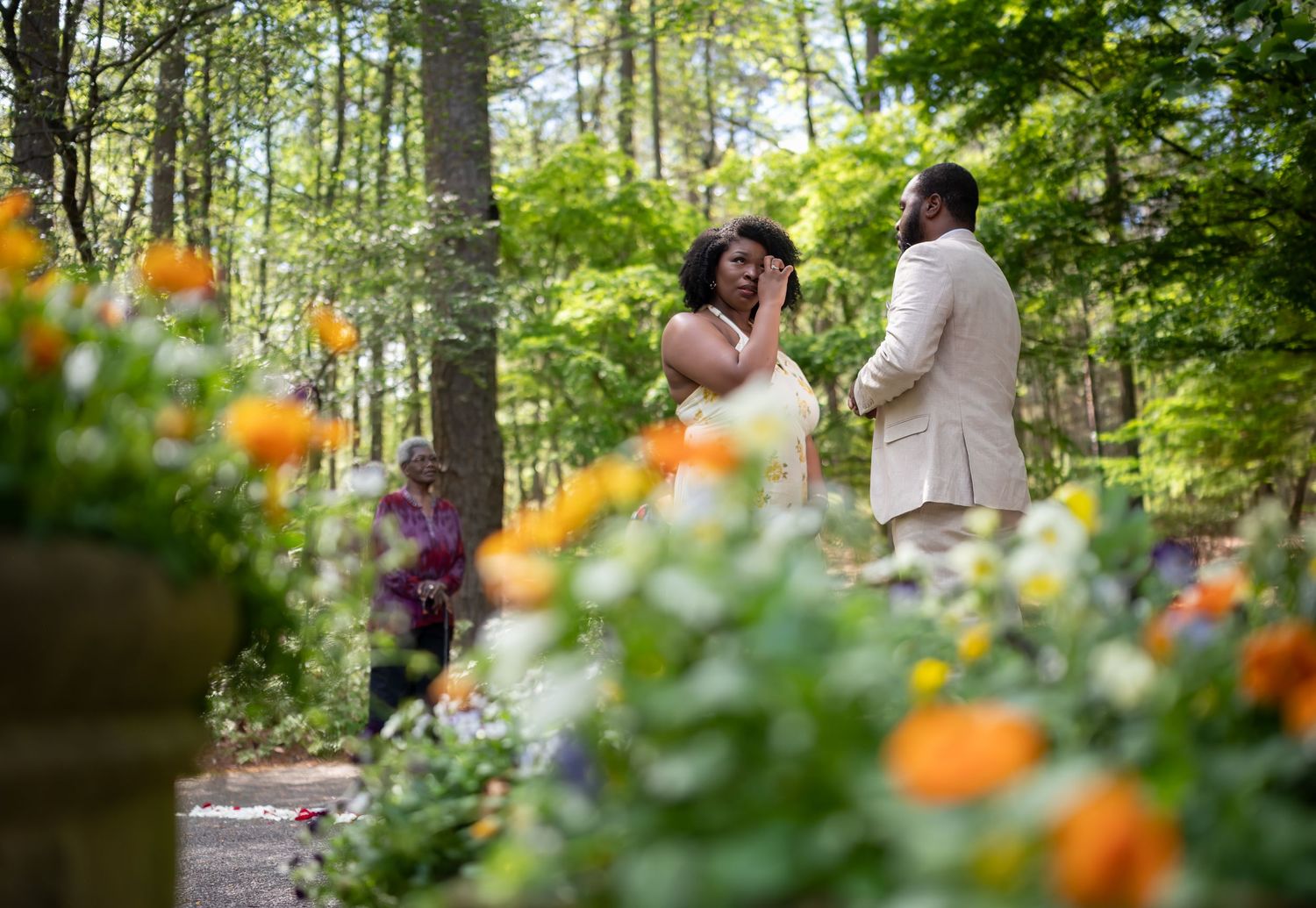 Romantic marriage proposal moment in lush garden with colorful orange and yellow flowers in the foreground.