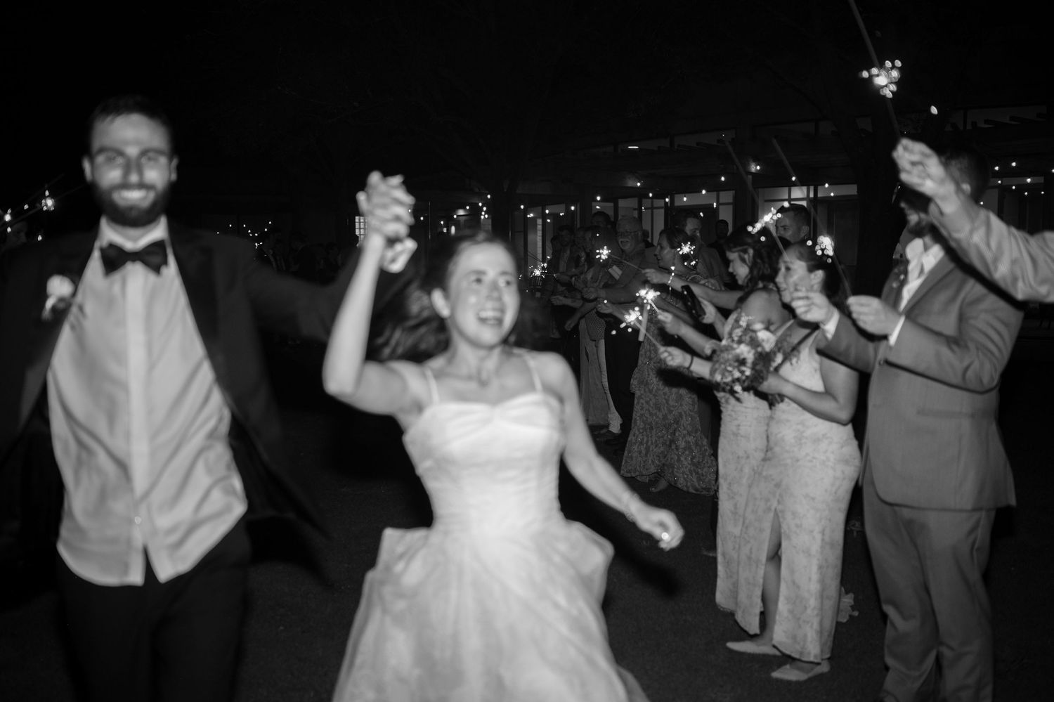 Wedding guests dancing and celebrating at a nighttime reception with a bride in a white dress on the dance floor.