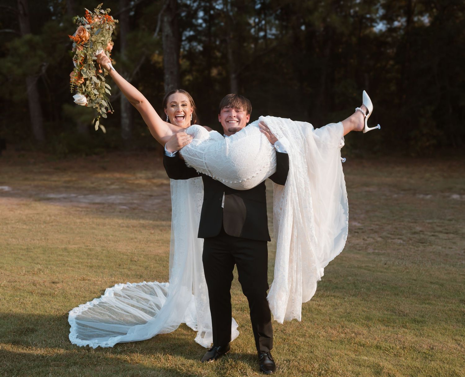 Wedding party celebrating outdoors with flowing white dress and veil in motion.