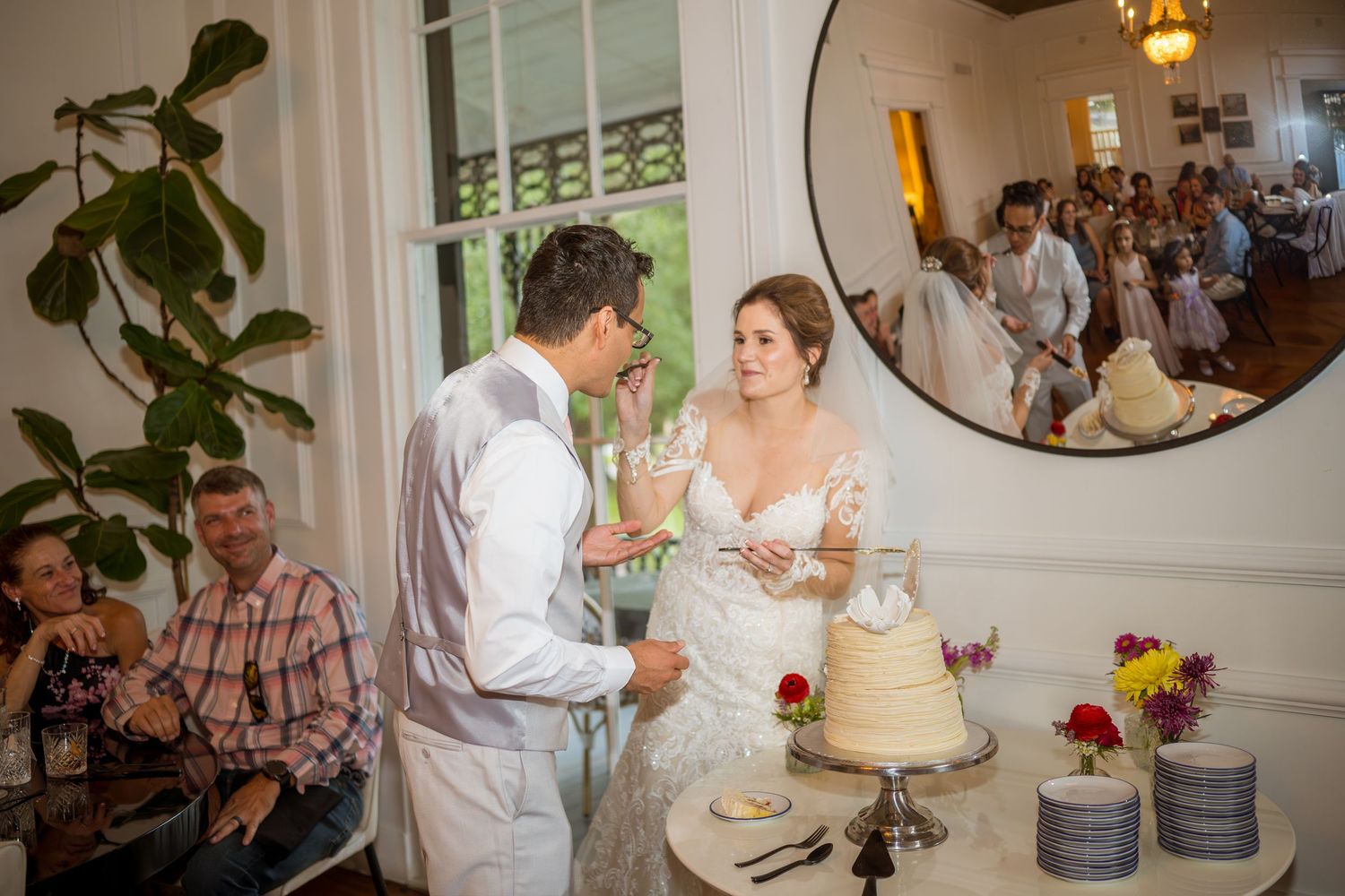 An elegant indoor wedding reception with floral centerpieces and cake cutting ceremony.
