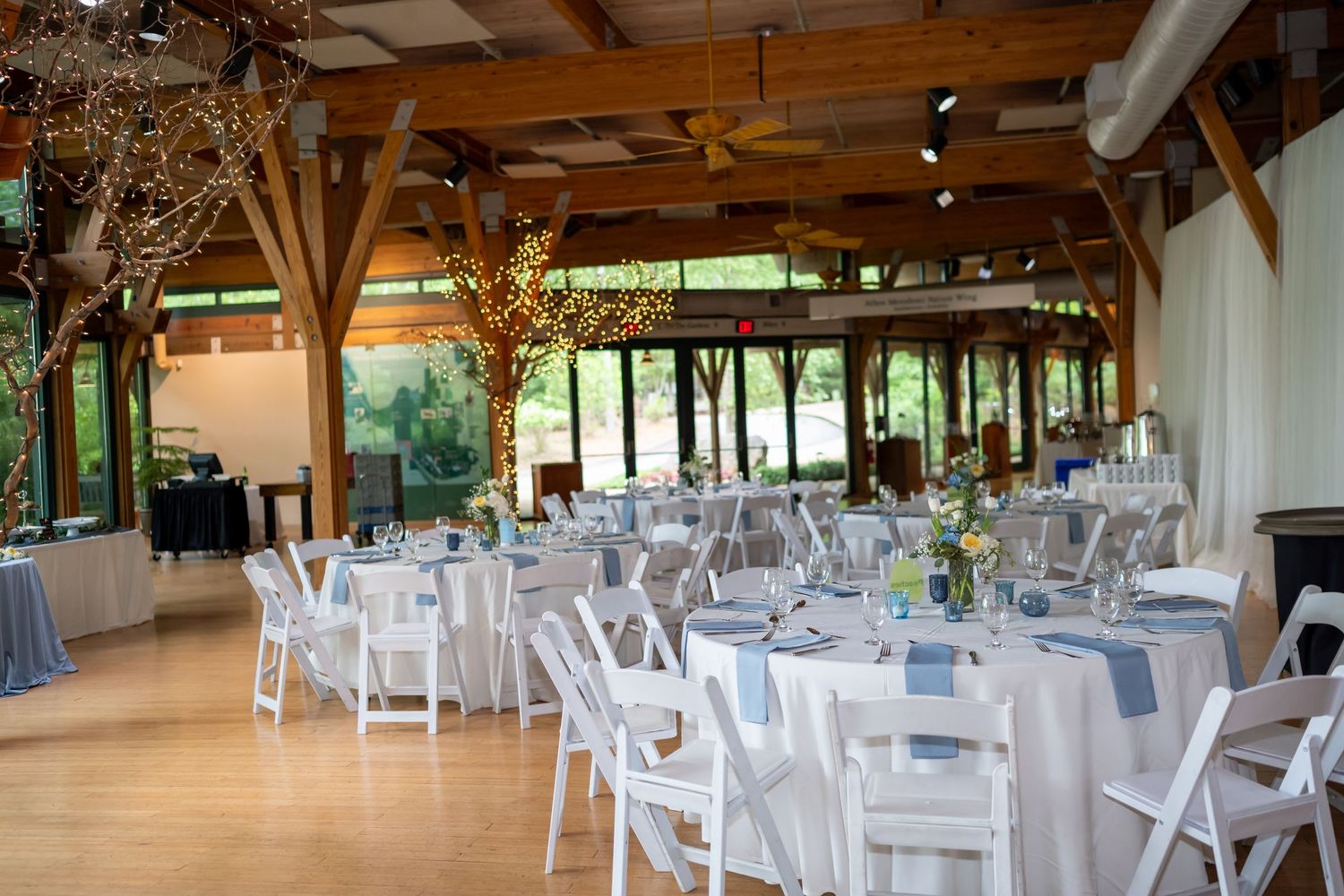 Rustic indoor wedding reception venue with exposed wooden beams and white decor.