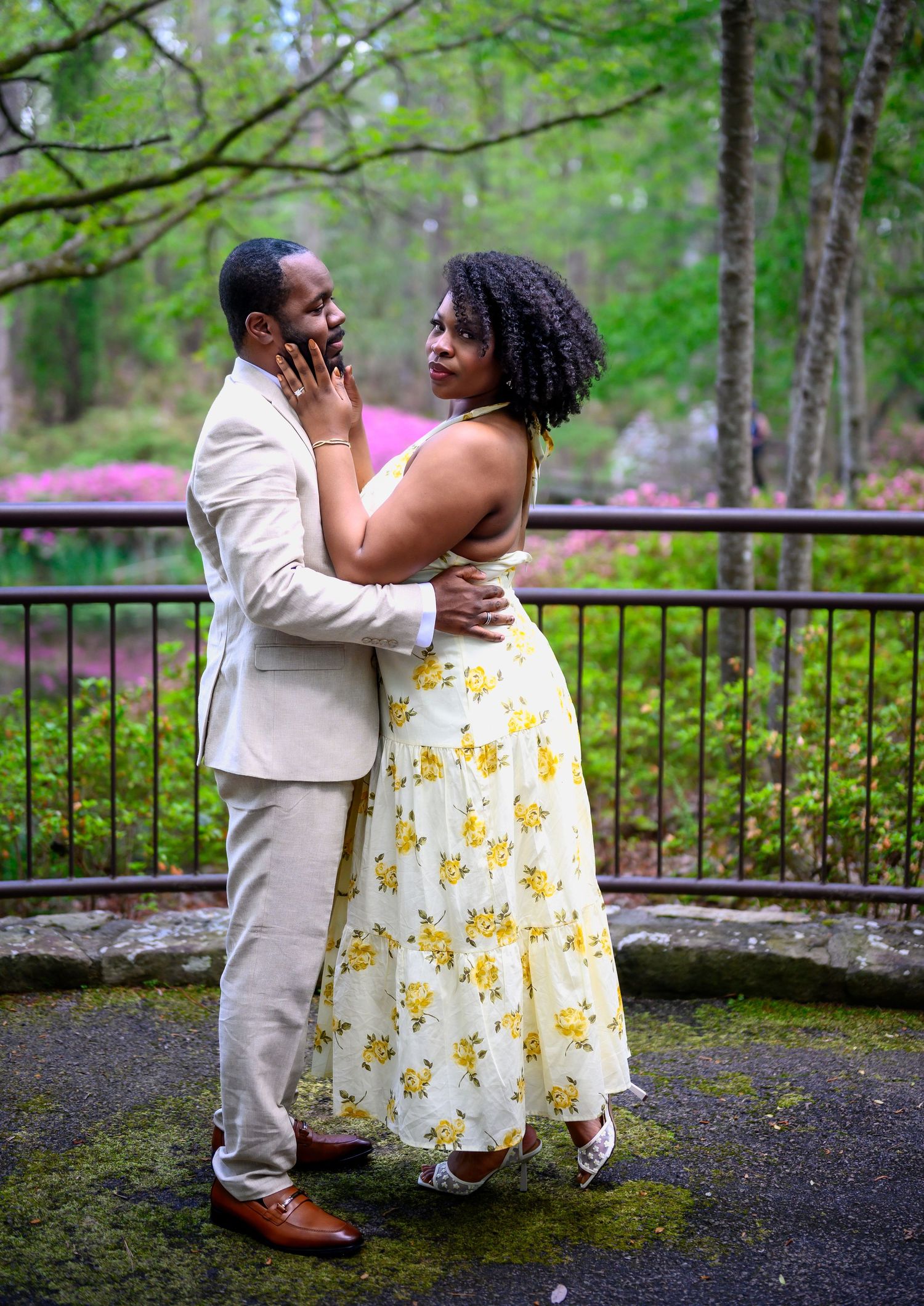 Couple sharing an intimate moment on a stone terrace surrounded by lush green garden scenery.