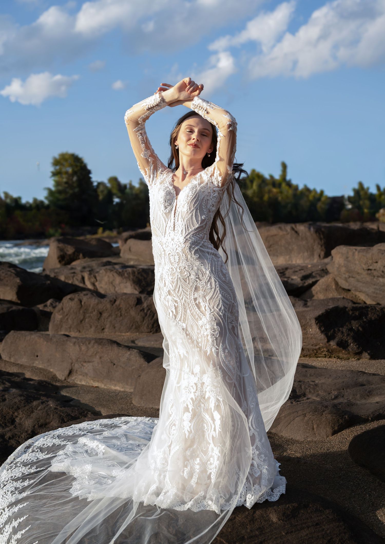 Ethereal bridal photos on rocky terrain with flowing white dress against blue sky backdrop.