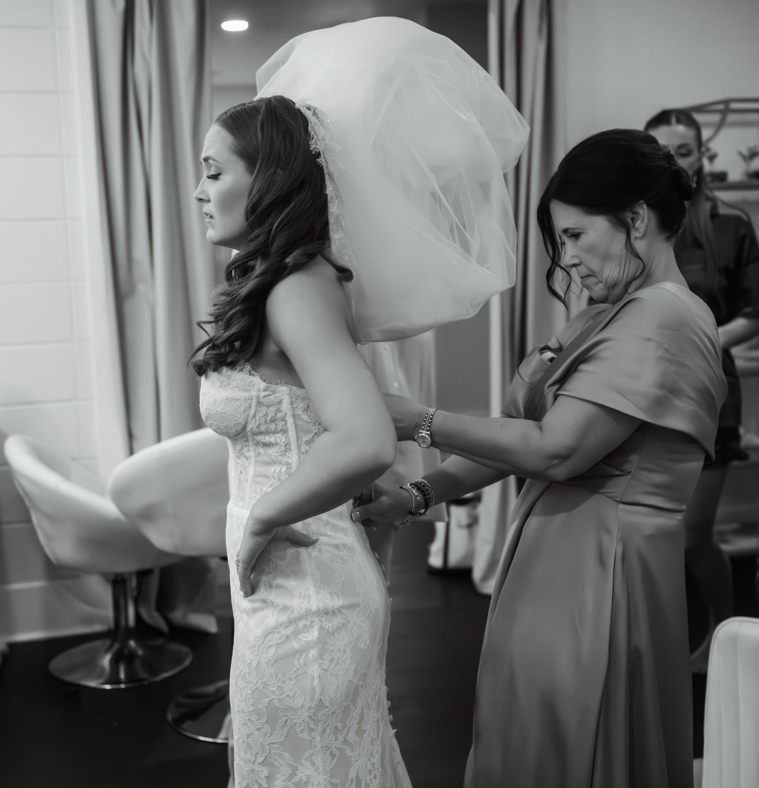 Black and white sequence showing the final dress adjustments before a wedding ceremony.